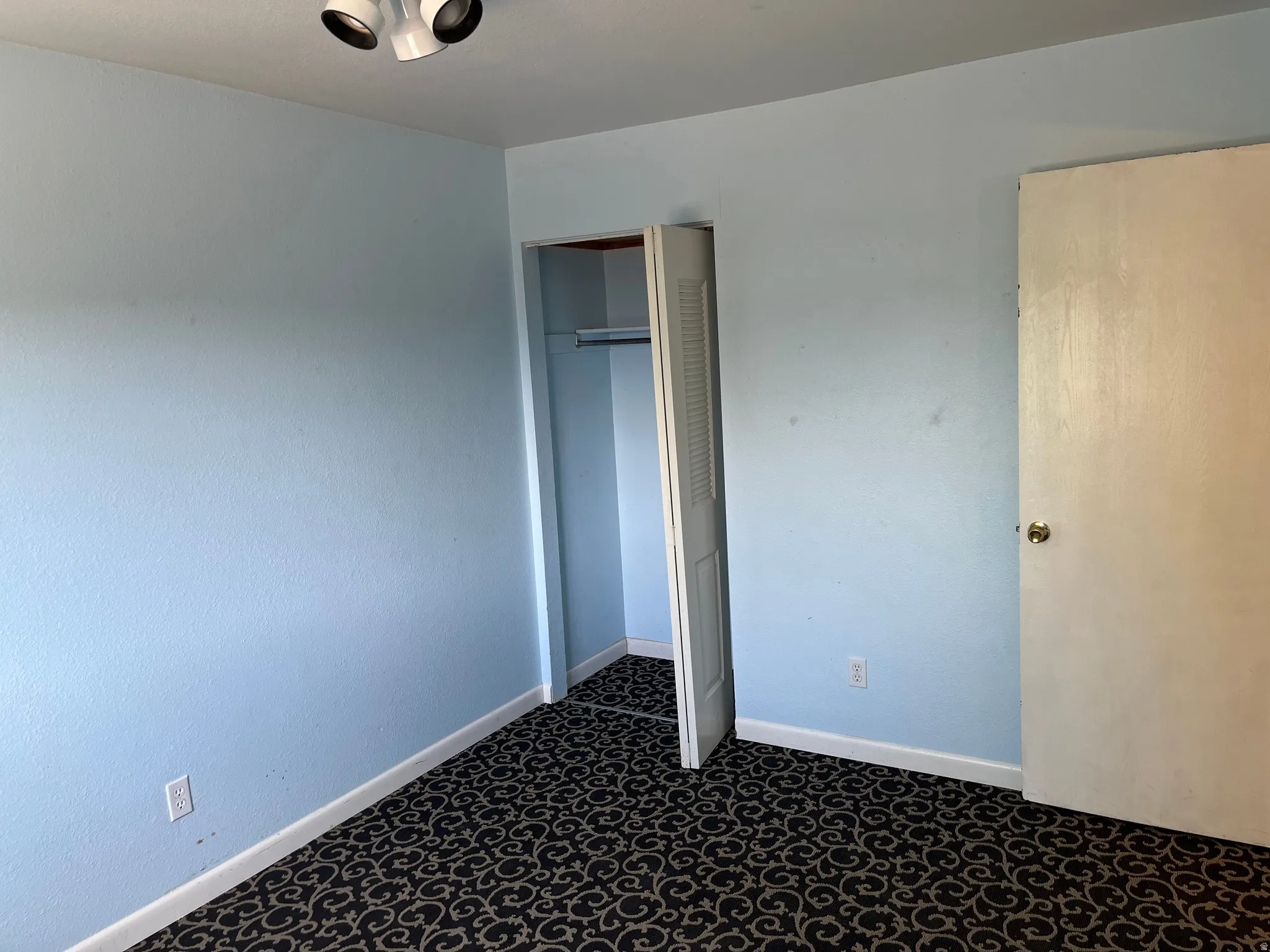 Unfurnished bedroom with a closet and dark carpet