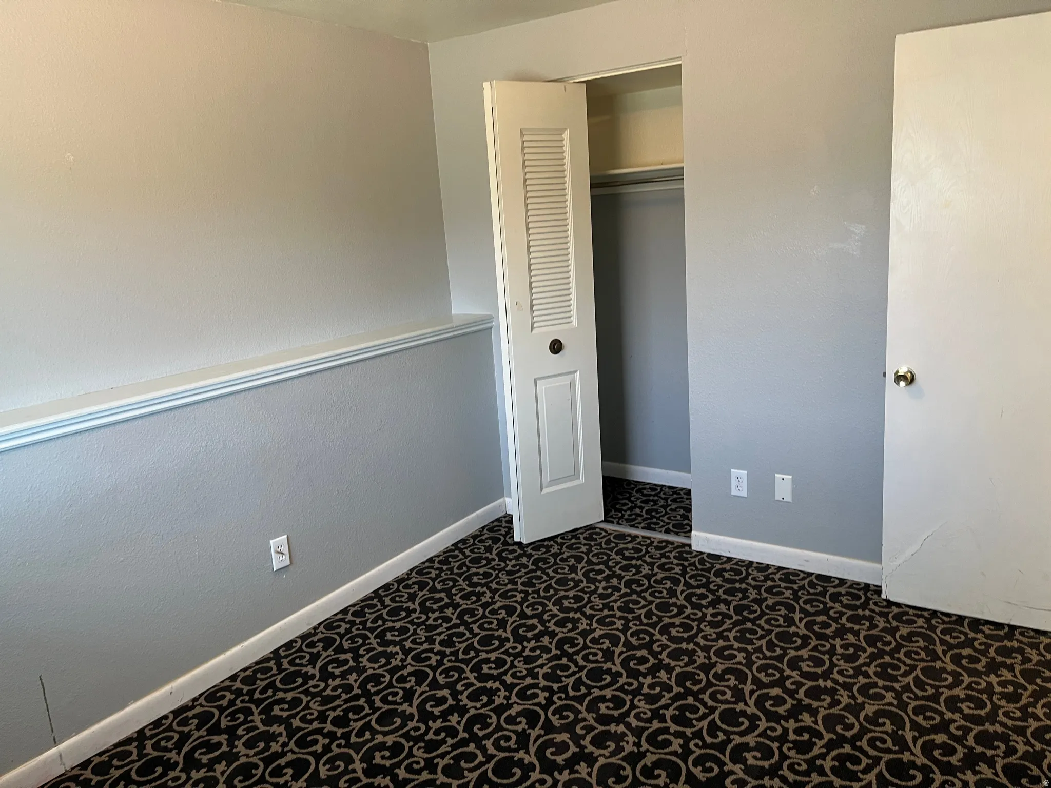 Unfurnished bedroom featuring a closet and dark carpet
