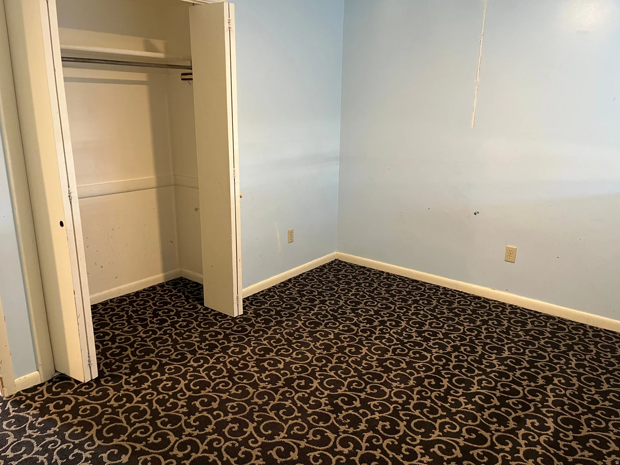 Unfurnished bedroom with a closet and dark carpet