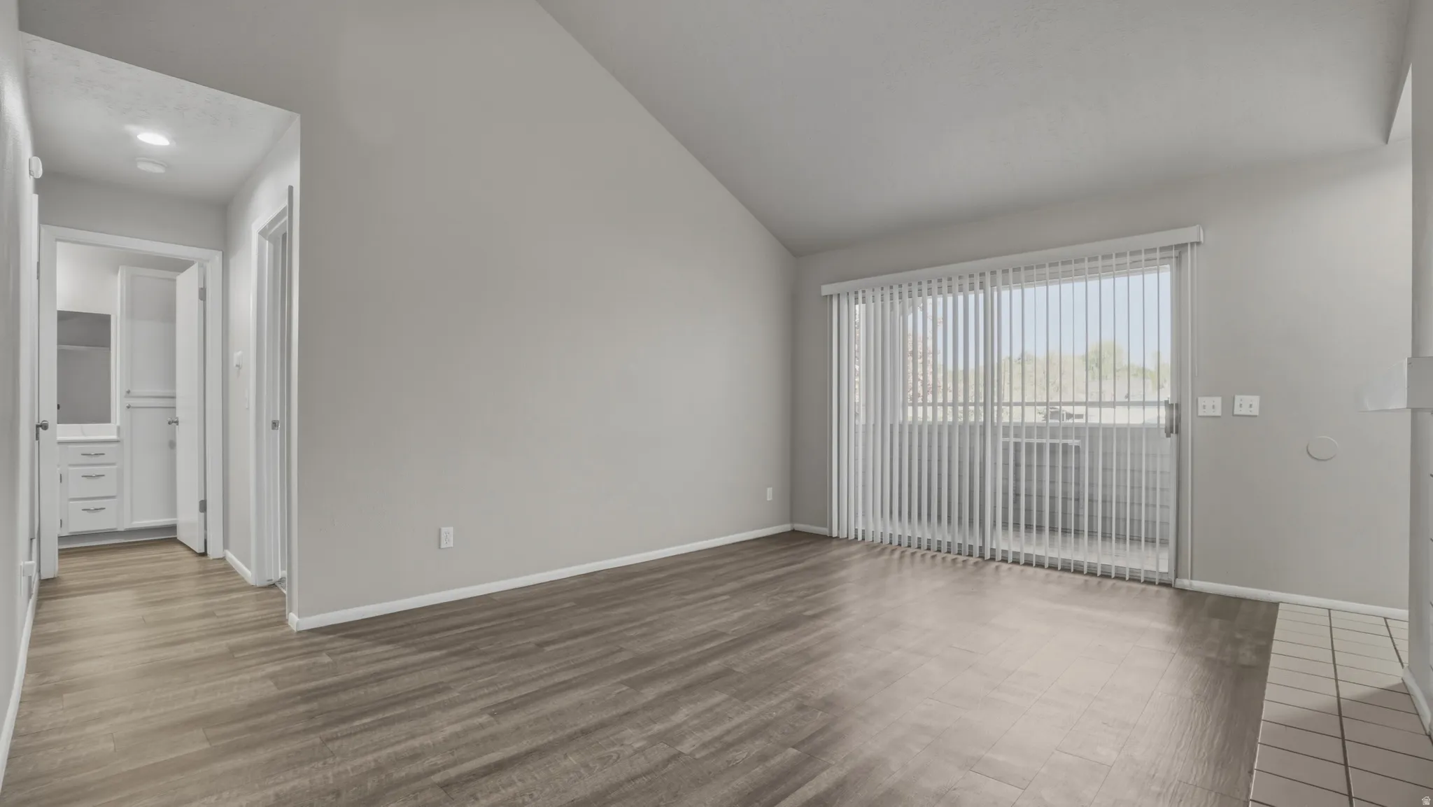 Spare room featuring dark wood finished floors and vaulted ceiling