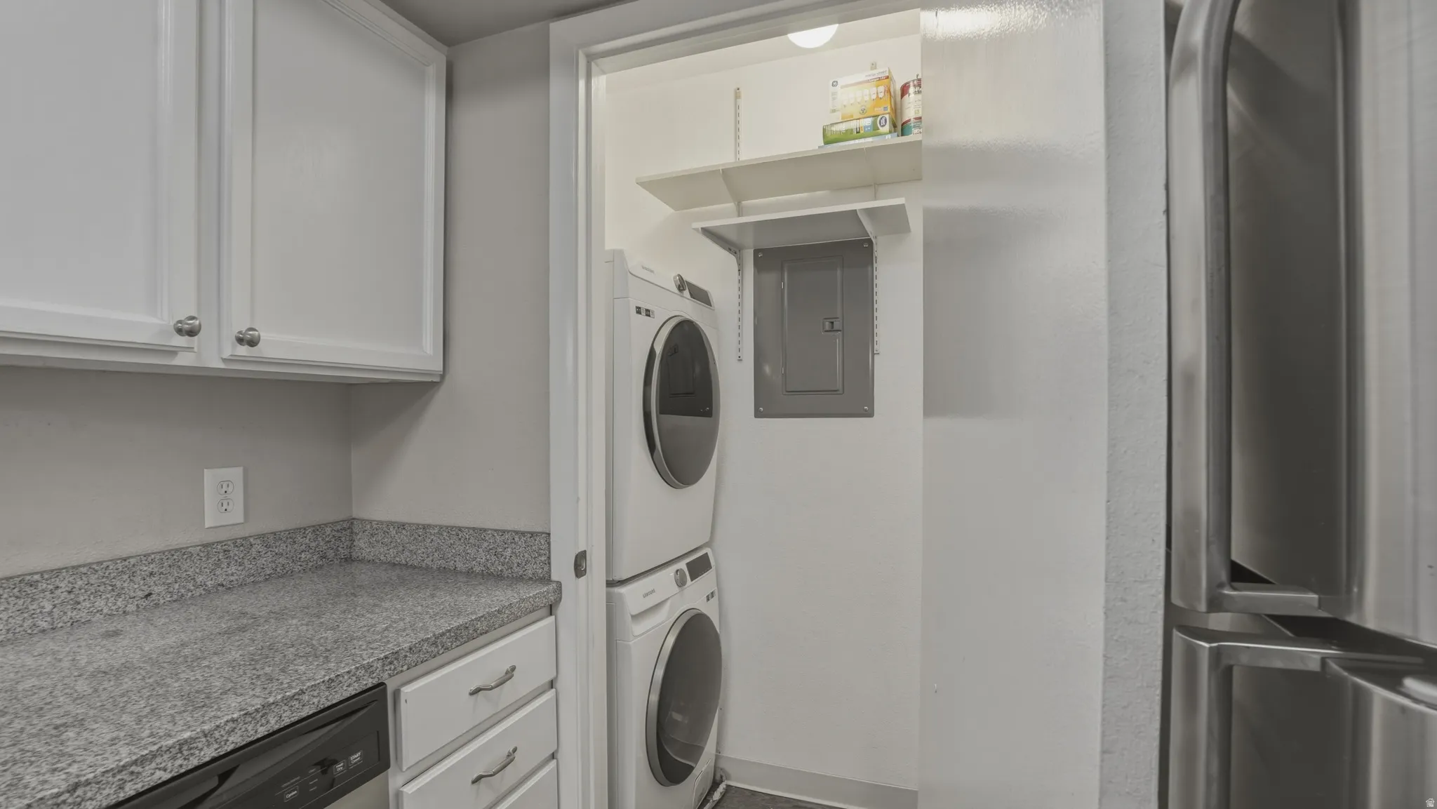 Laundry area with electric panel and stacked washer / dryer