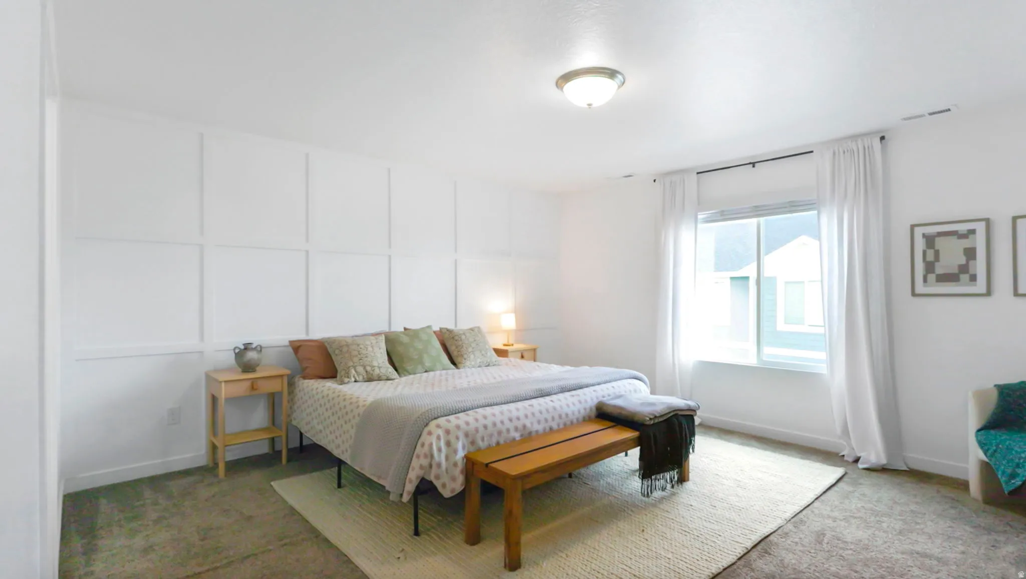 Primary bedroom with a decorative wall and natural light