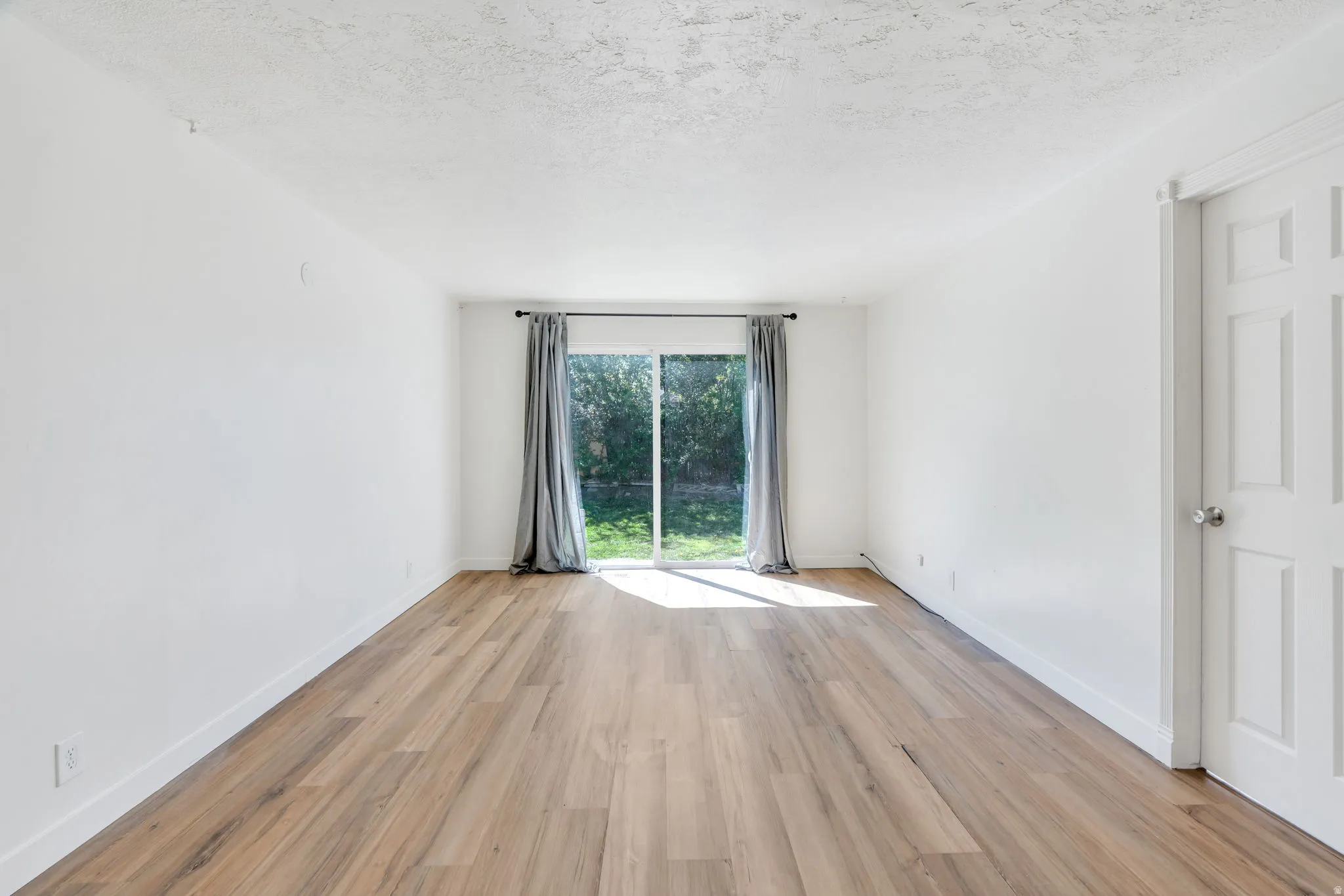 Spare room featuring light wood-type flooring and a textured ceiling