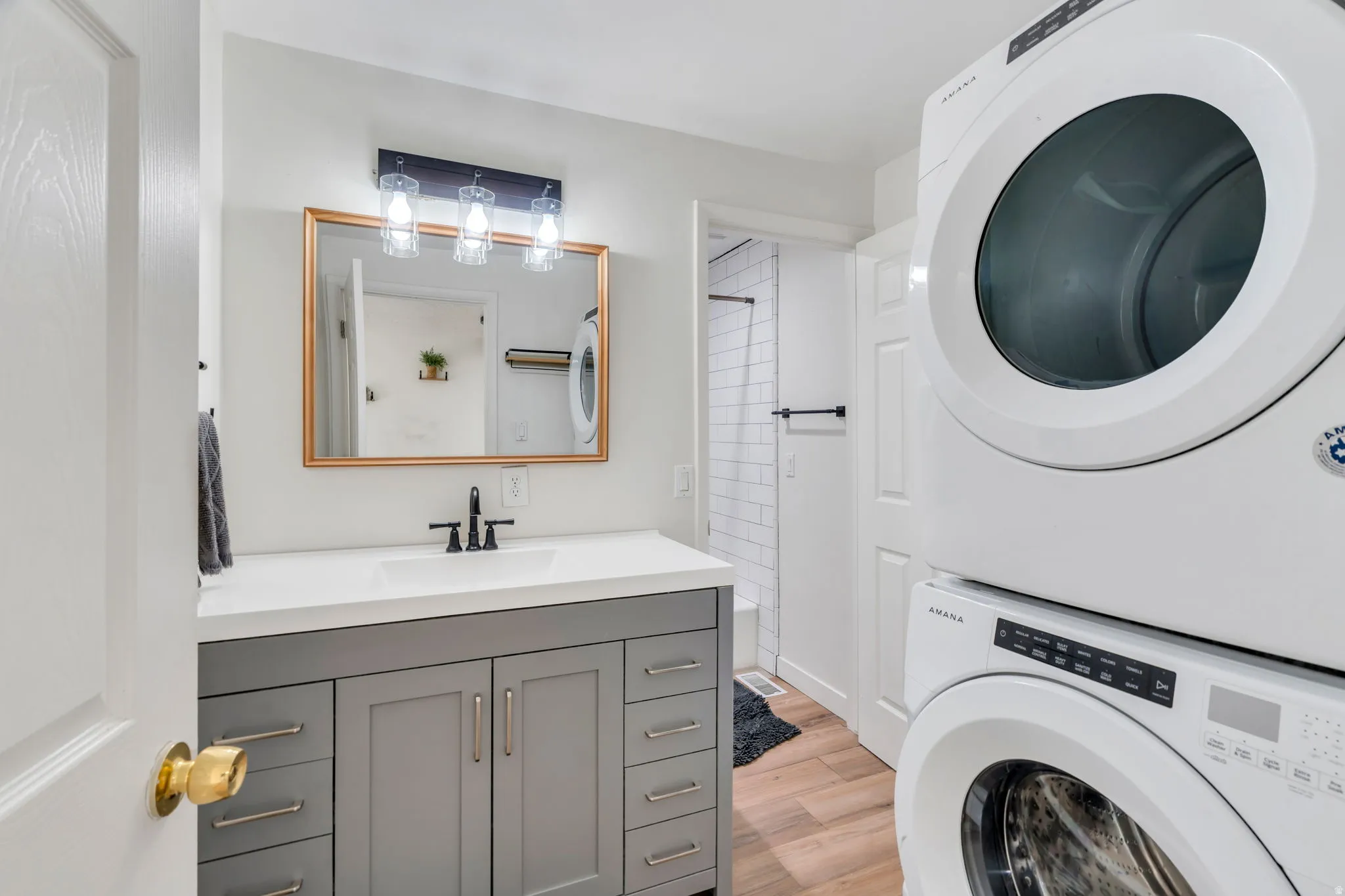 Laundry area featuring light wood-type flooring and stacked washer / dryer