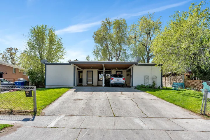 Mid-century home with concrete driveway, a carport, stucco siding, and a gate