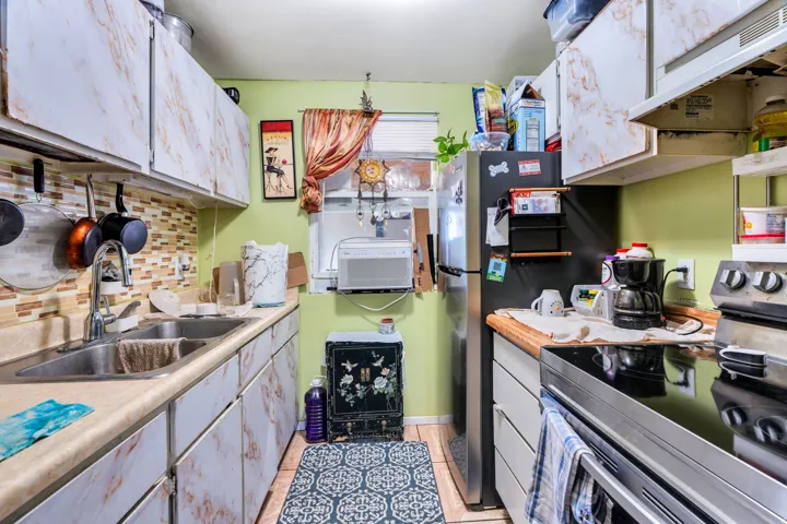 Kitchen featuring stainless steel appliances, tasteful backsplash, light countertops, and white cabinetry