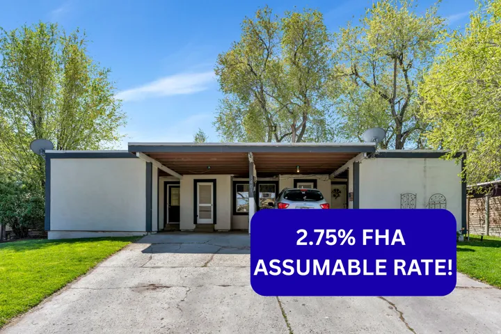 View of front facade with a carport, driveway, stucco siding, and a front yard