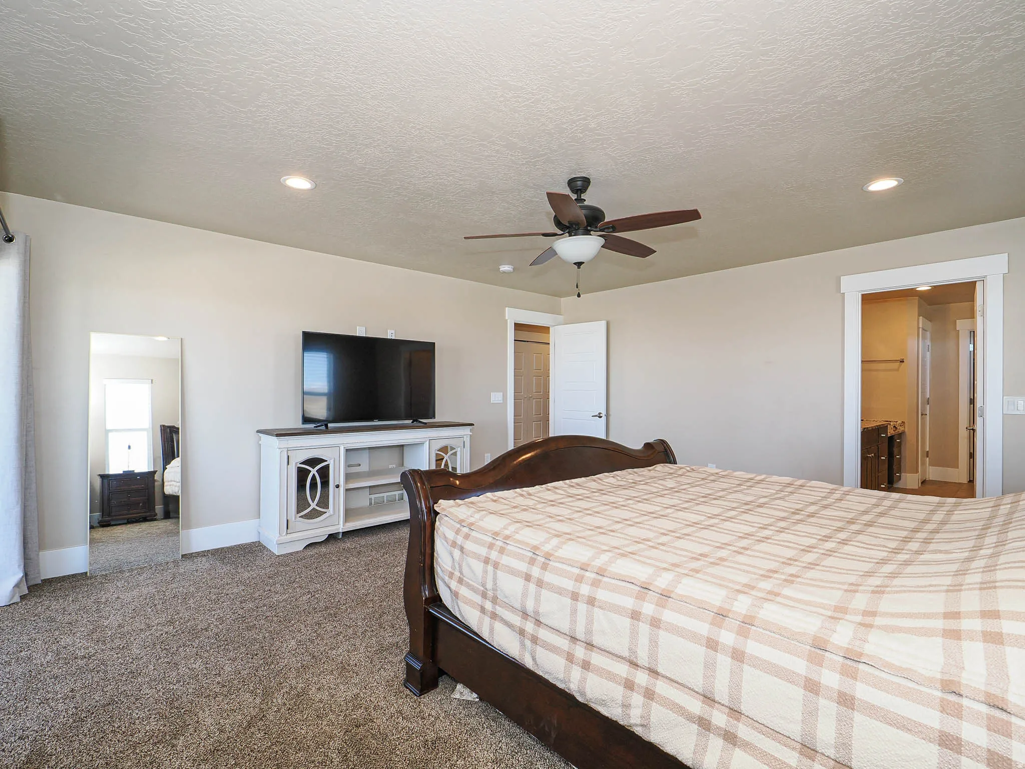 Bedroom with dark carpet, ceiling fan, a textured ceiling, recessed lighting, and ensuite bathroom
