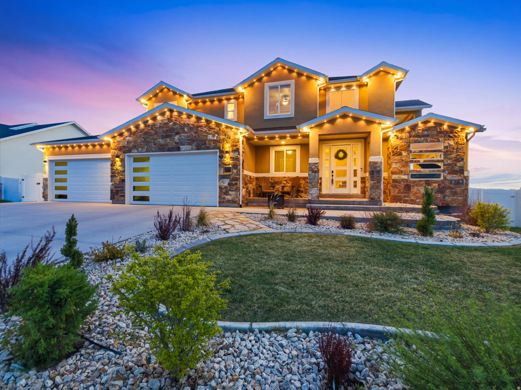 View of front facade with a garage, stone siding, concrete driveway, and a porch
