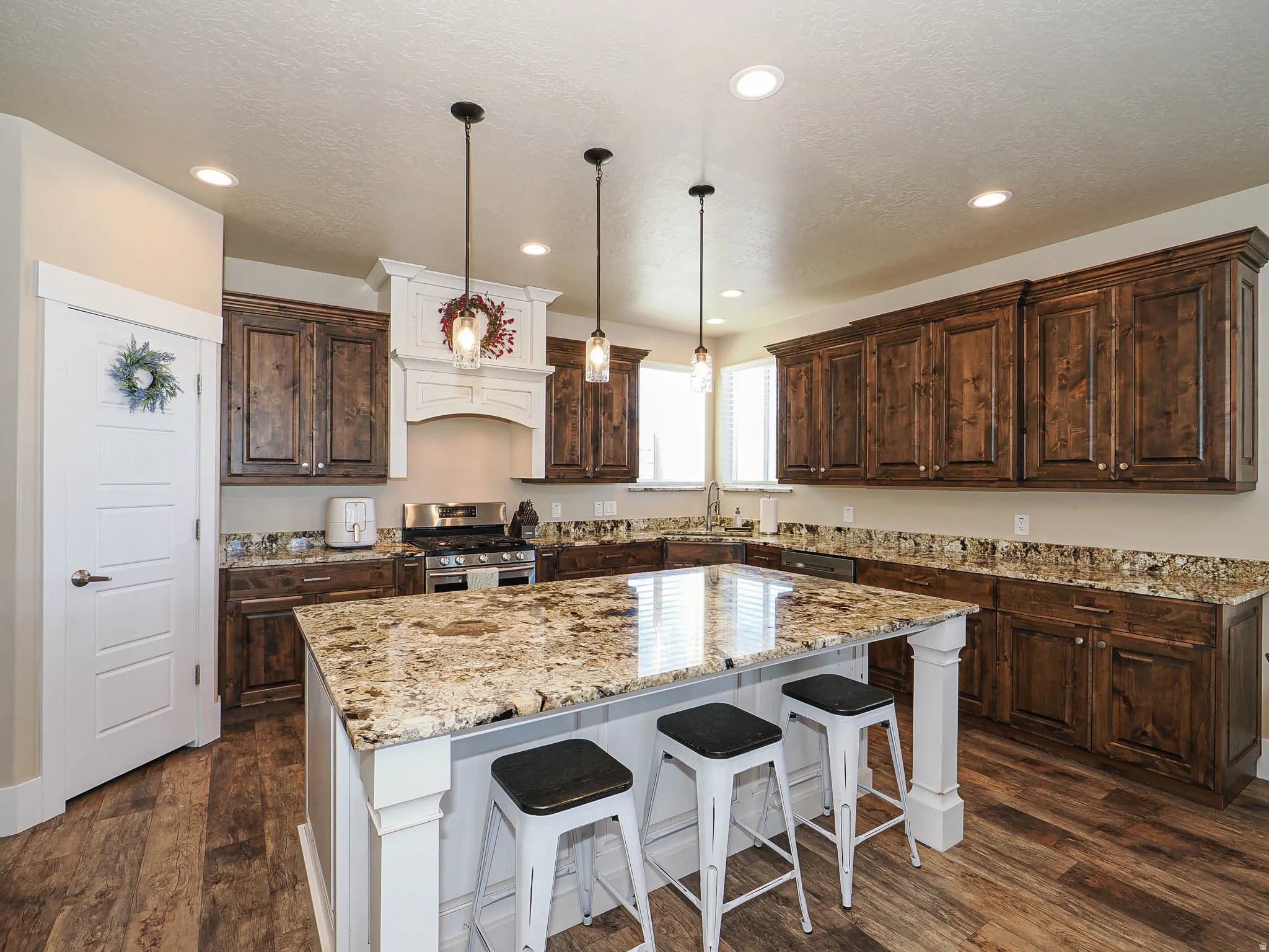 Kitchen featuring dark wood finish cabinetry, a kitchen bar, a center island, stainless steel gas range, and dark wood-style flooring