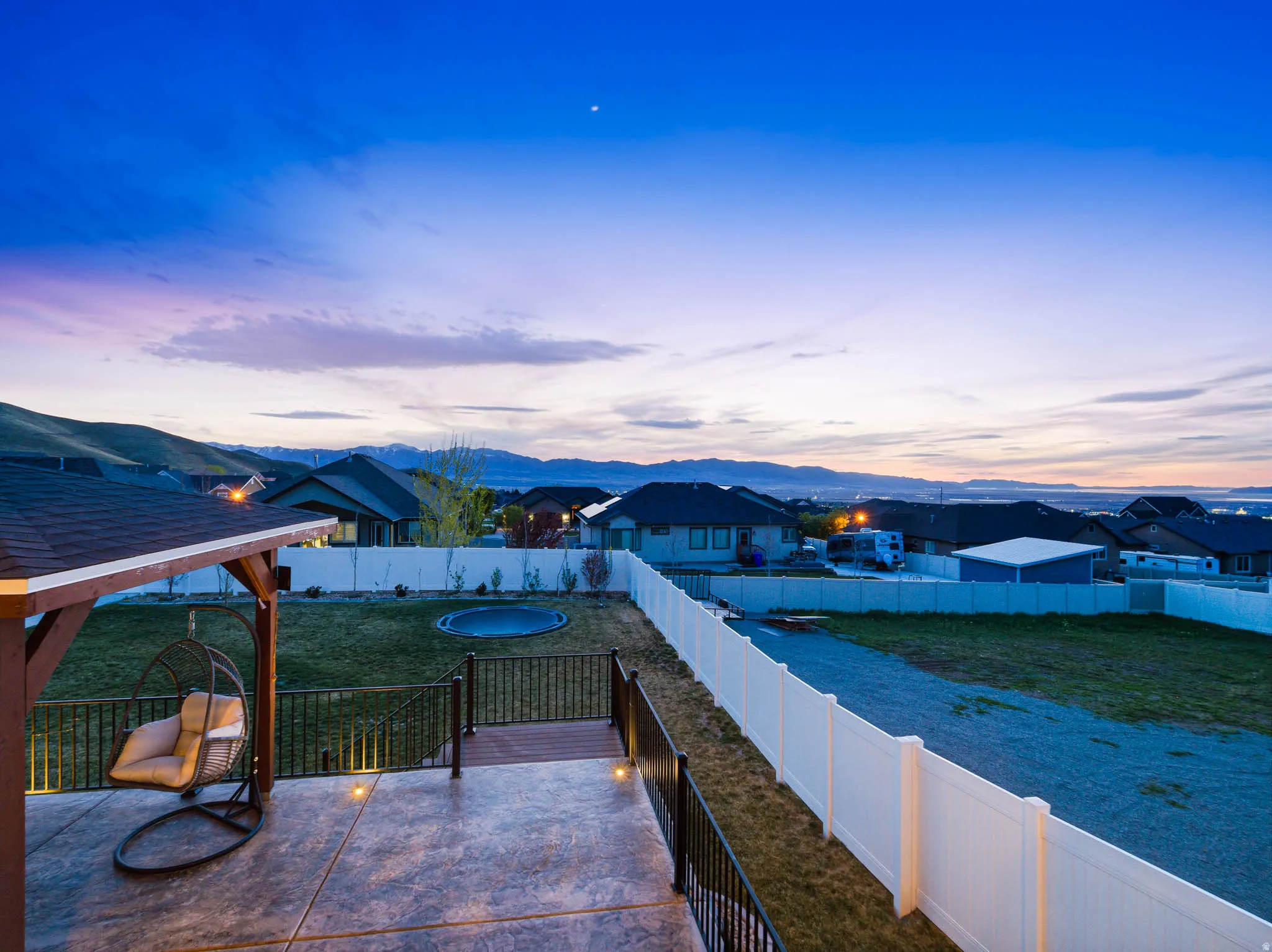 Patio terrace at dusk featuring a mountain view, a patio, a fenced backyard, a gazebo, and a residential view