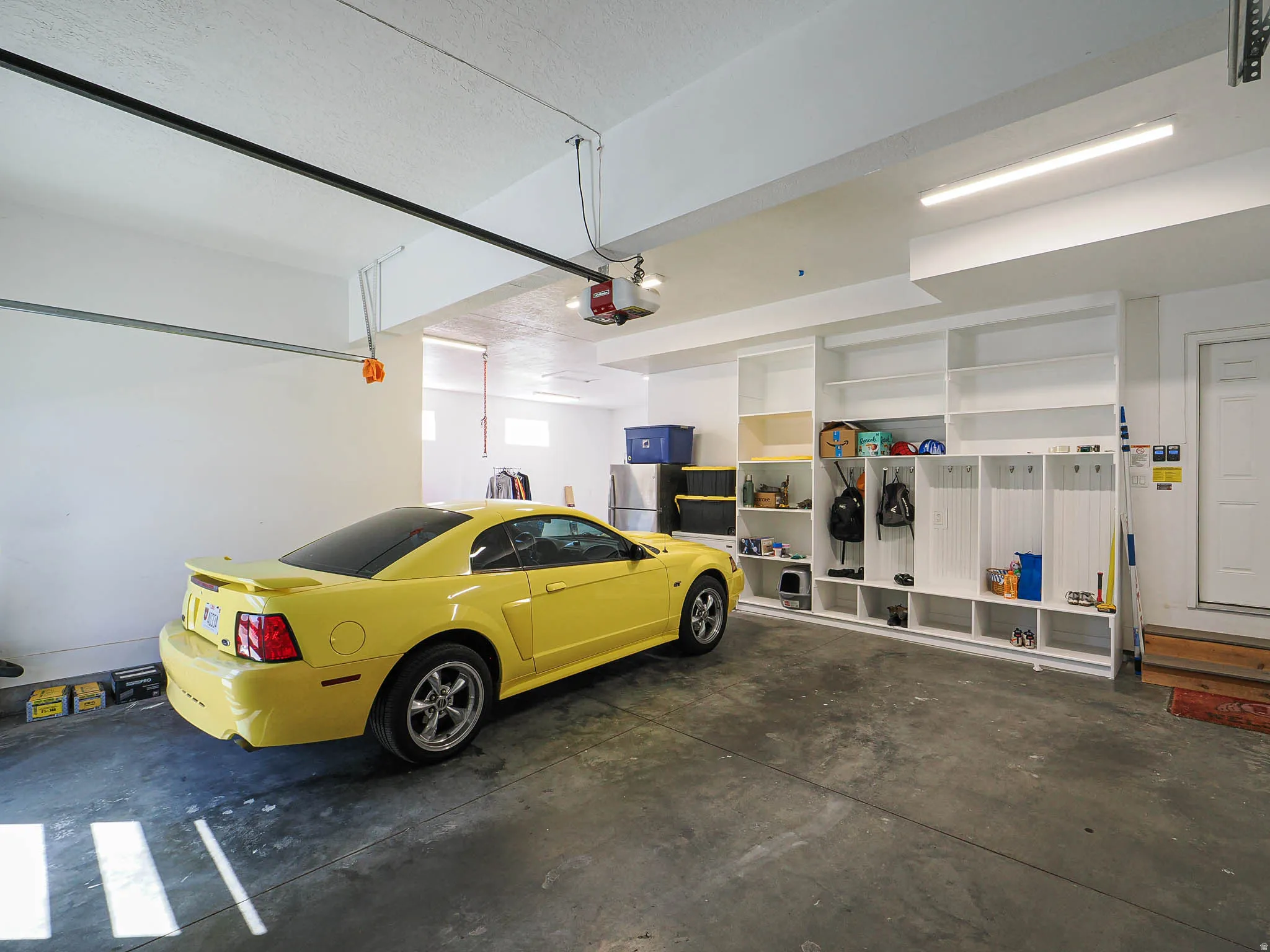Garage featuring freestanding refrigerator and a garage door opener