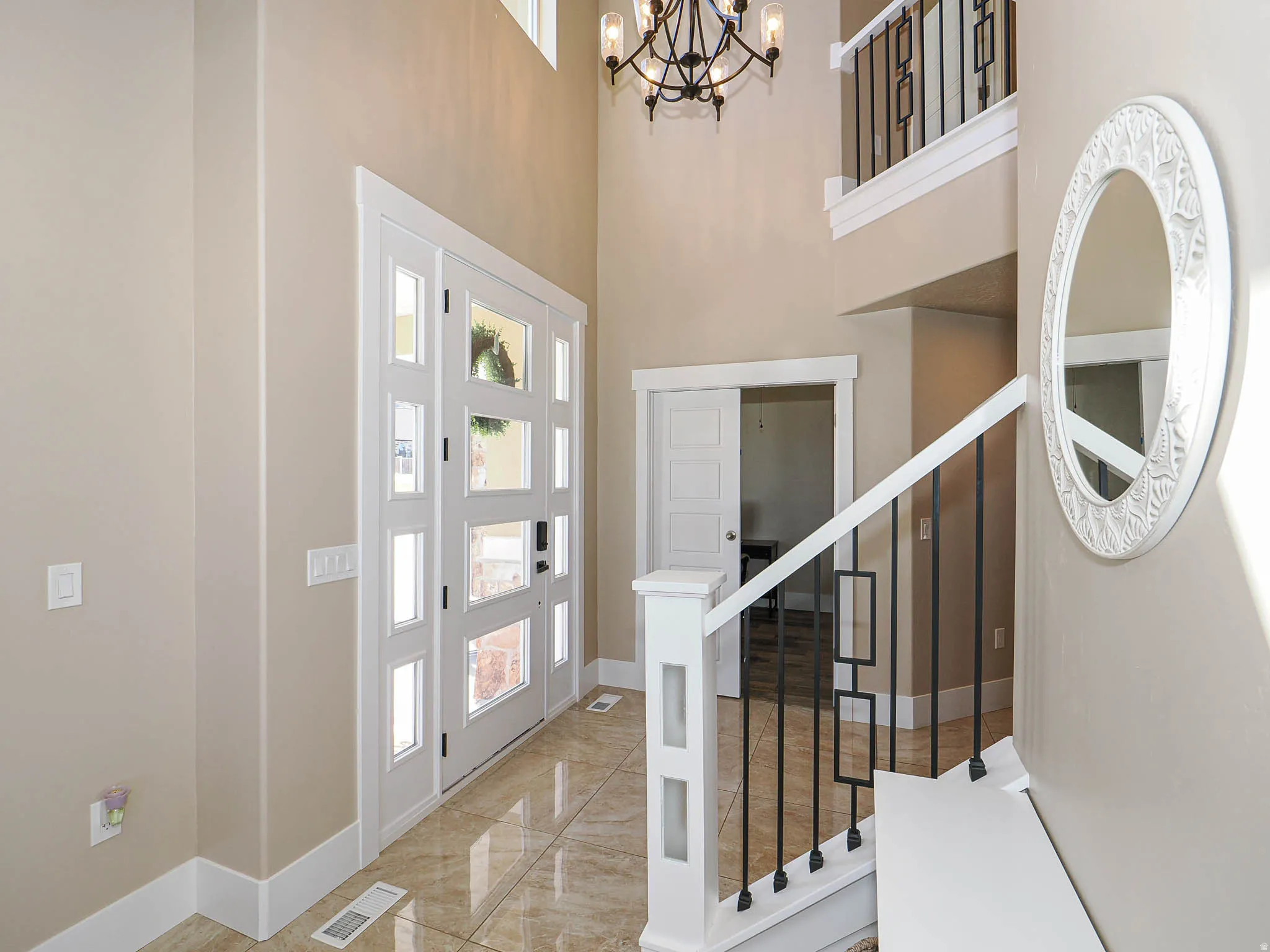 Entrance foyer with a high ceiling, suspended lighting, and light marble finish flooring