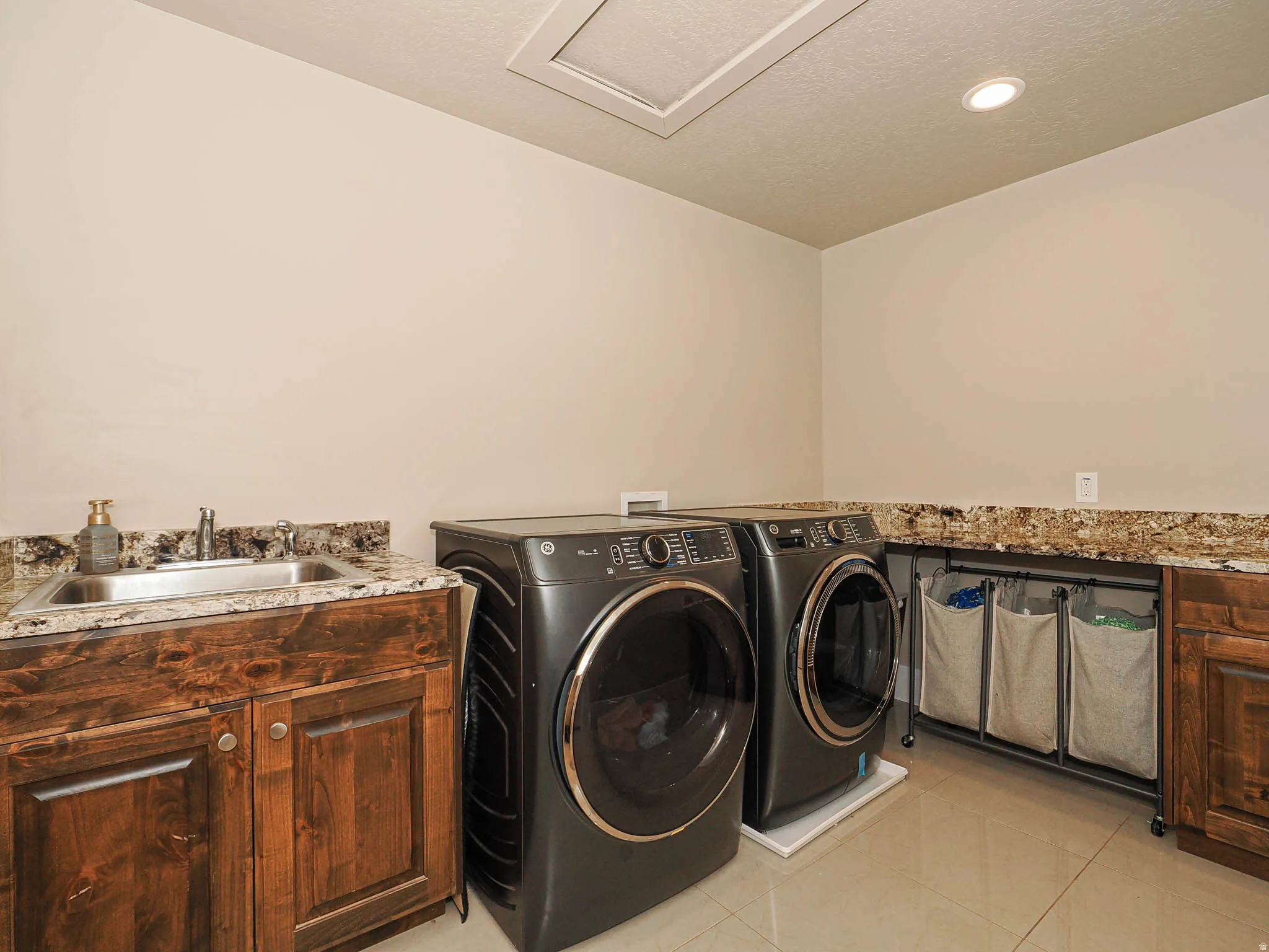 Laundry area with light tile patterned floors, washing machine and dryer, cabinet space, recessed lighting, and a textured ceiling