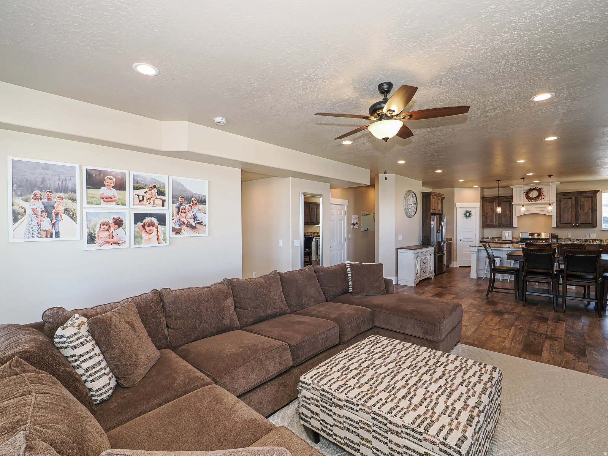Living area with a textured ceiling, recessed lighting, ceiling fan, and dark wood-type flooring