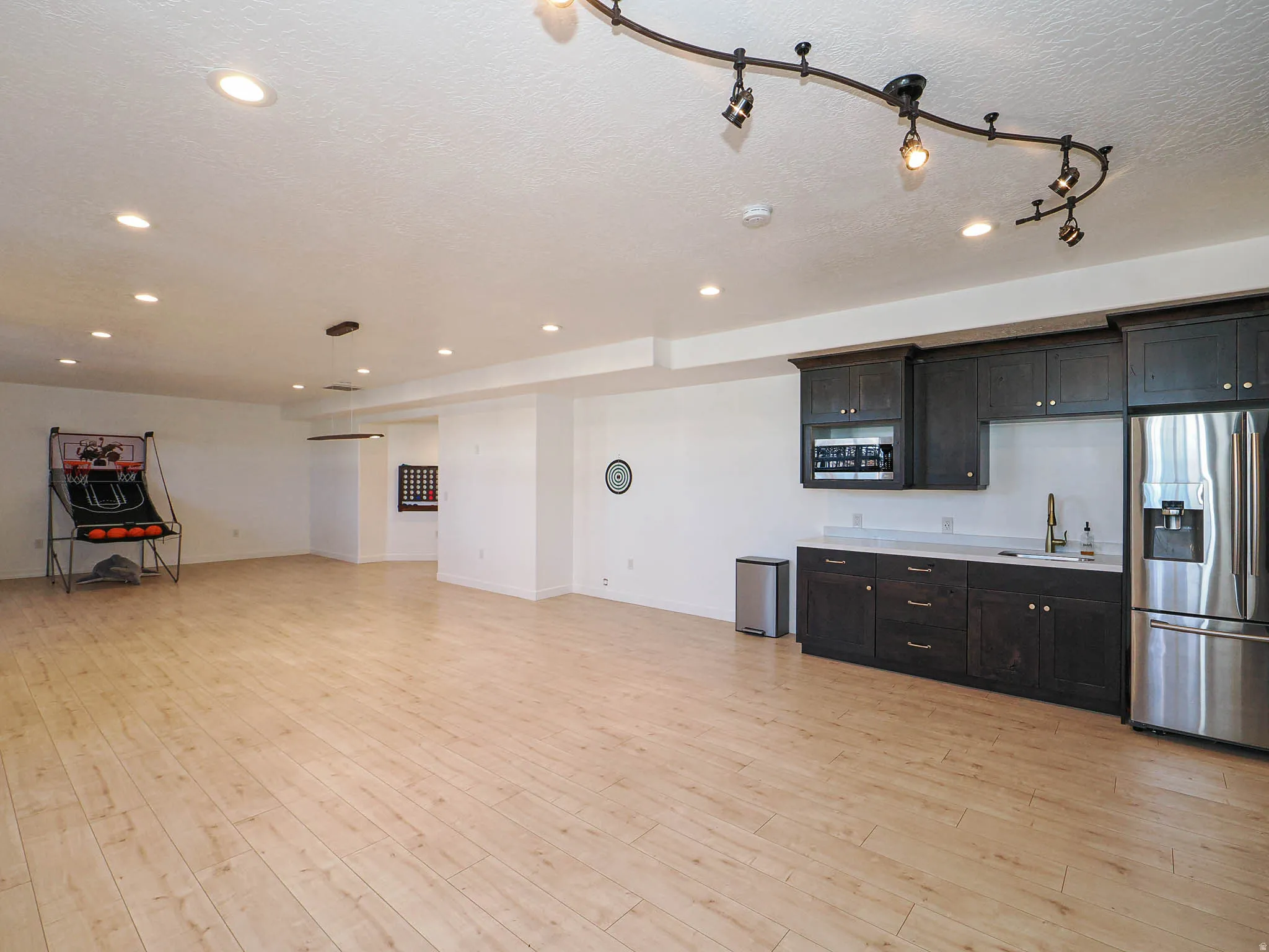 Kitchen with light countertops, stainless steel appliances, light wood-type flooring, a textured ceiling, and open floor plan