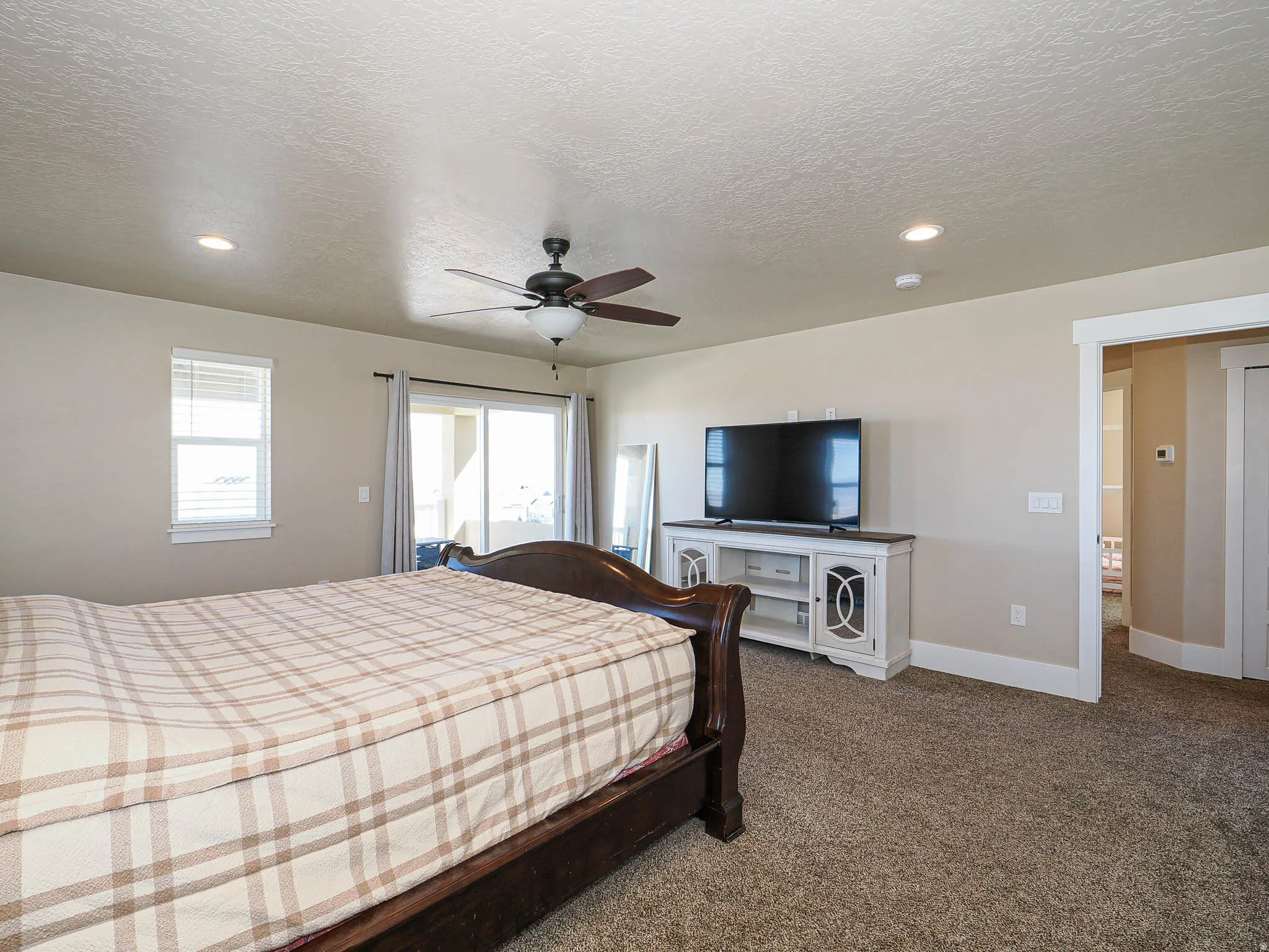 Bedroom featuring access to exterior, dark colored carpet, a textured ceiling, a ceiling fan, and recessed lighting