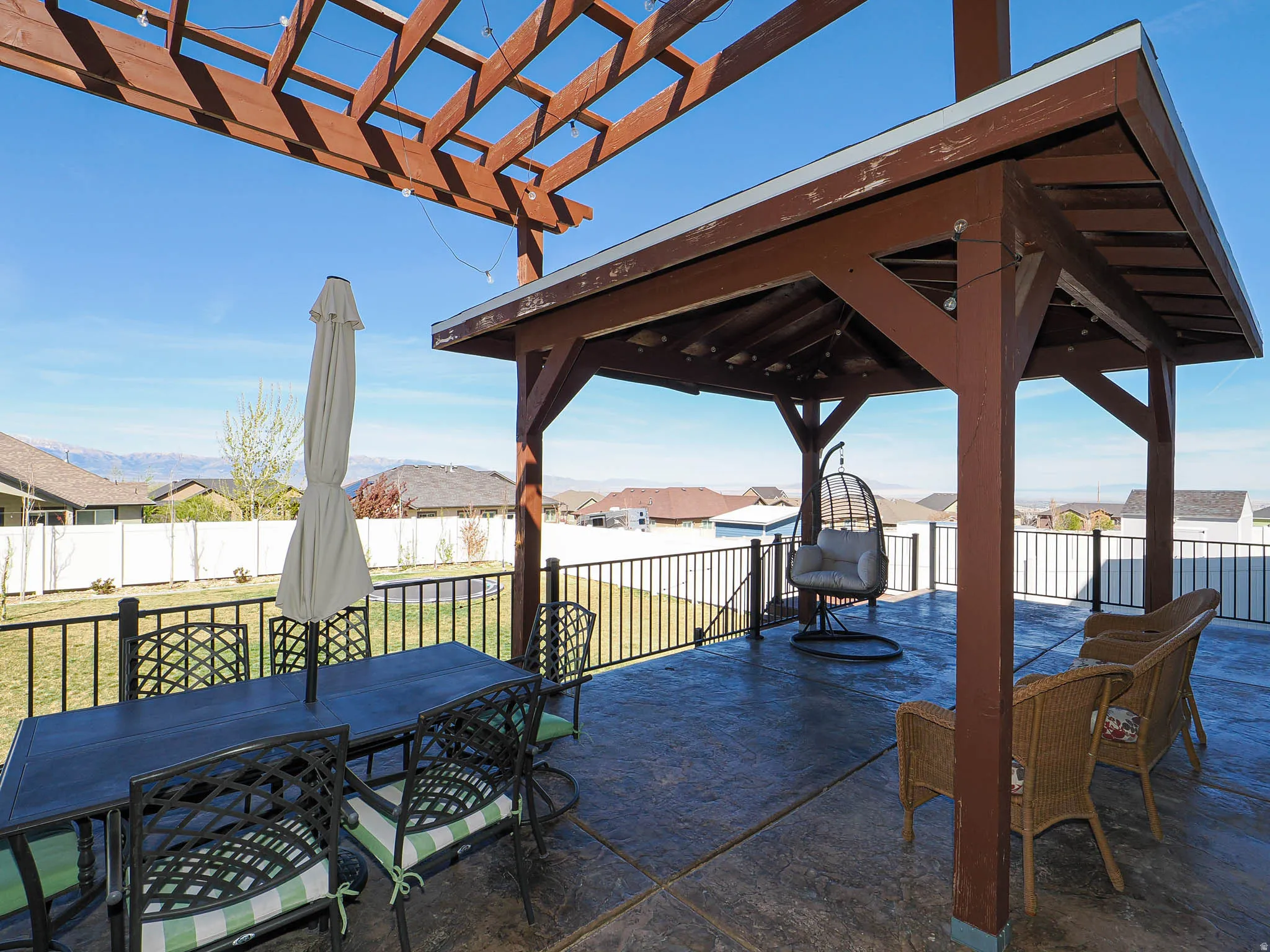 Fenced backyard featuring outdoor dining area, a residential view, a patio, a pergola, and a gazebo