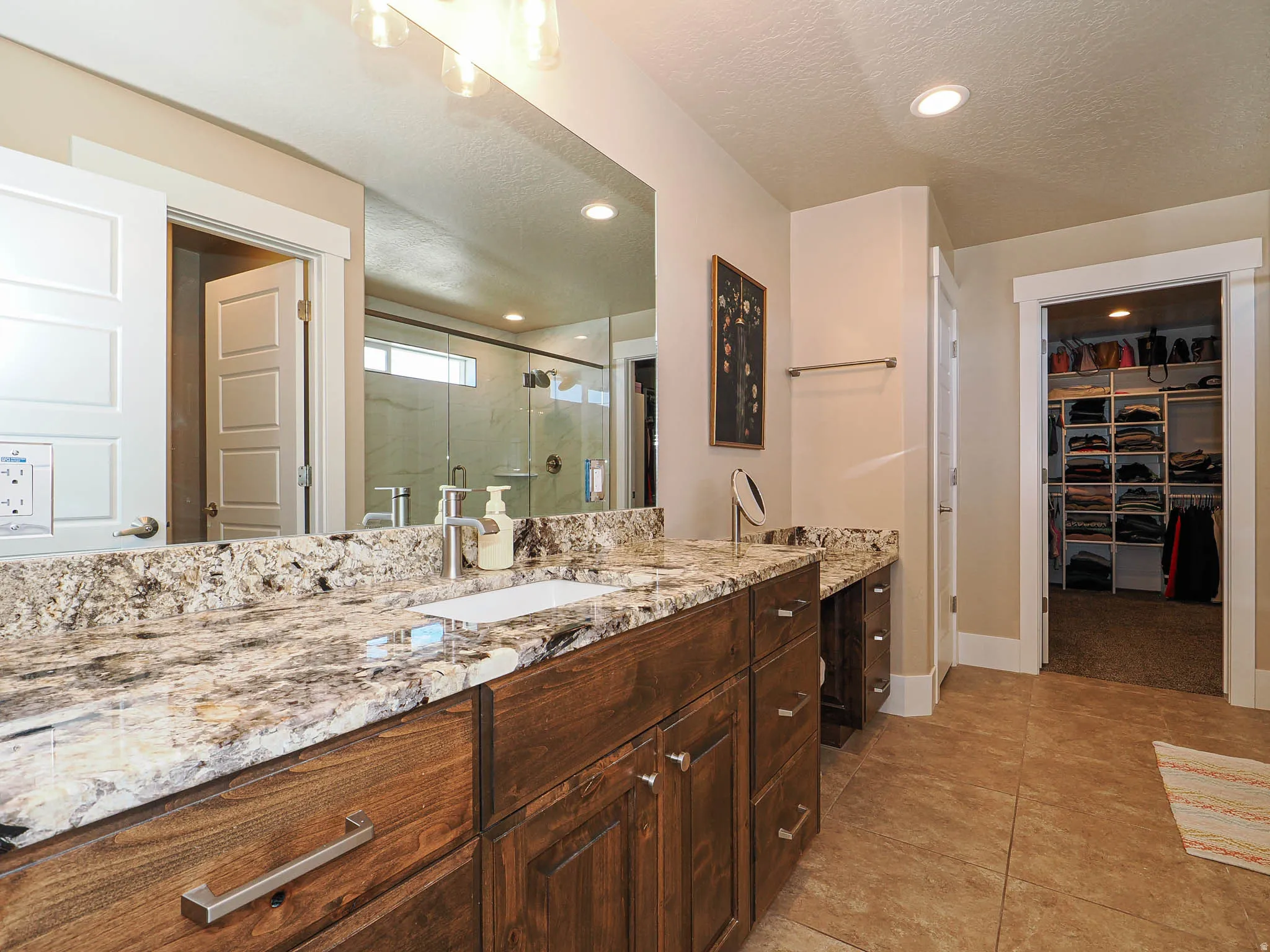 Bathroom featuring a spacious closet, vanity, a textured ceiling, a shower stall, and recessed lighting