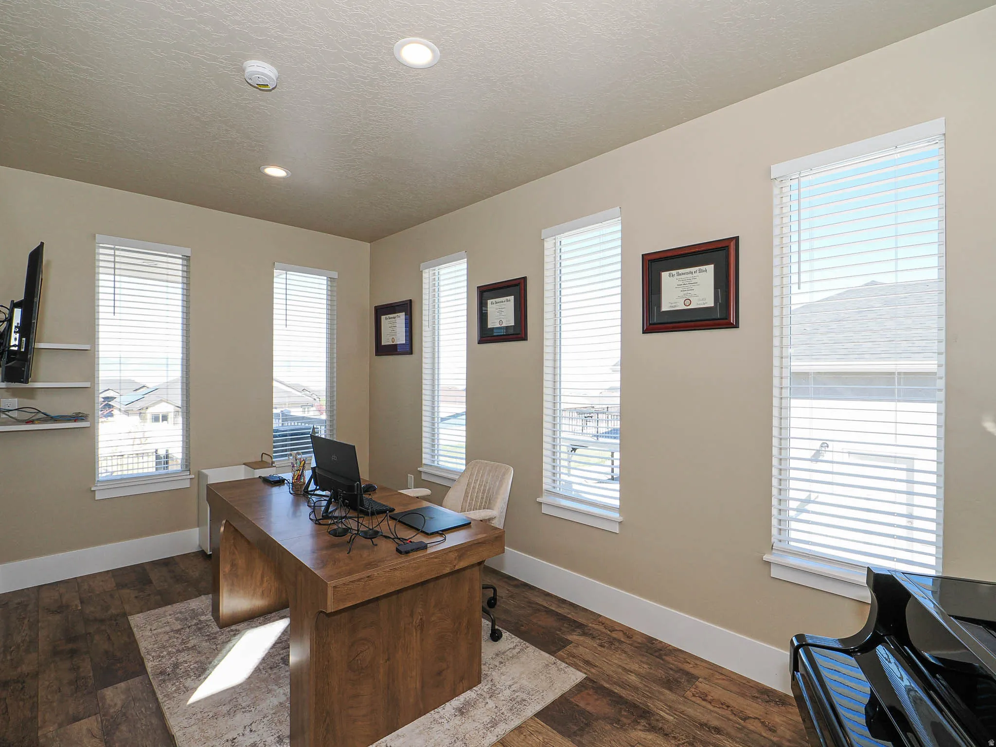 Office area with dark wood-type flooring, healthy amount of natural light, a textured ceiling, and recessed lighting