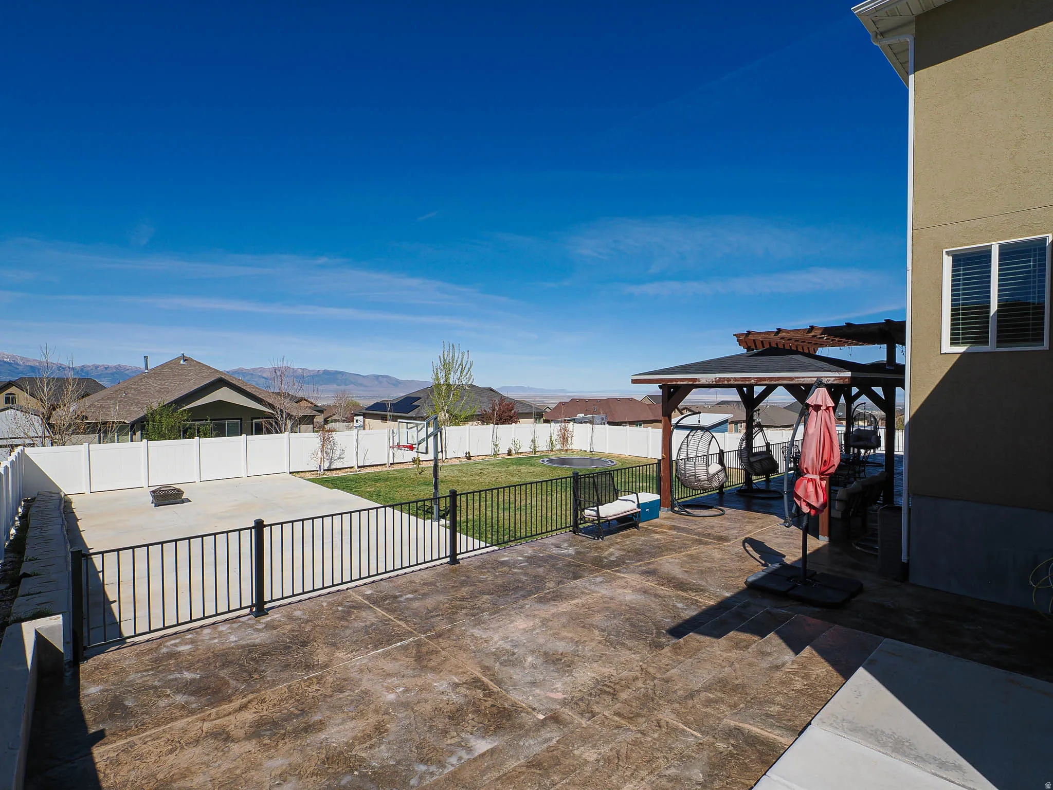Fenced backyard with a gazebo, a patio area, a residential view, and a mountain view