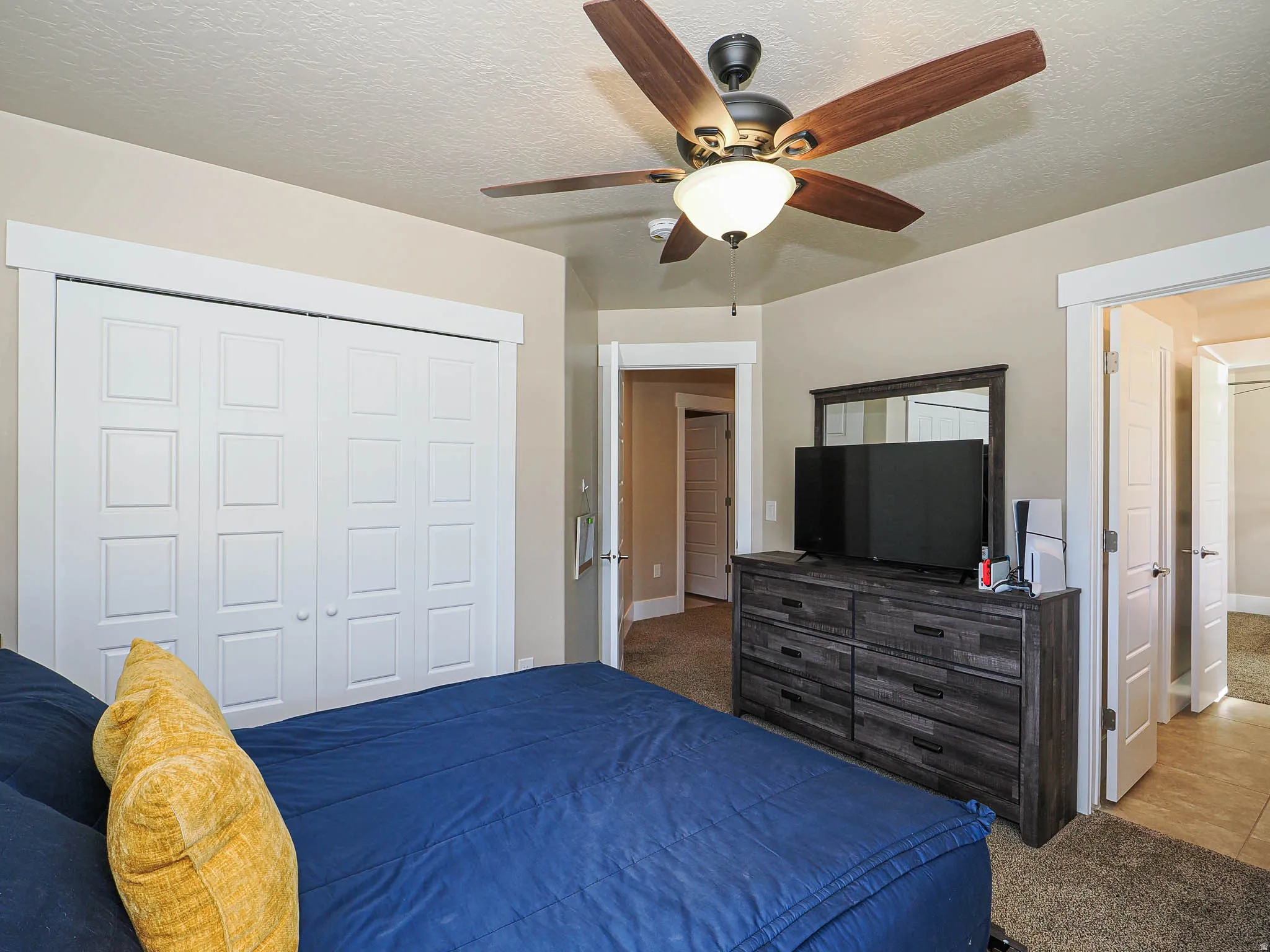 Carpeted bedroom featuring a textured ceiling, a ceiling fan, and a closet