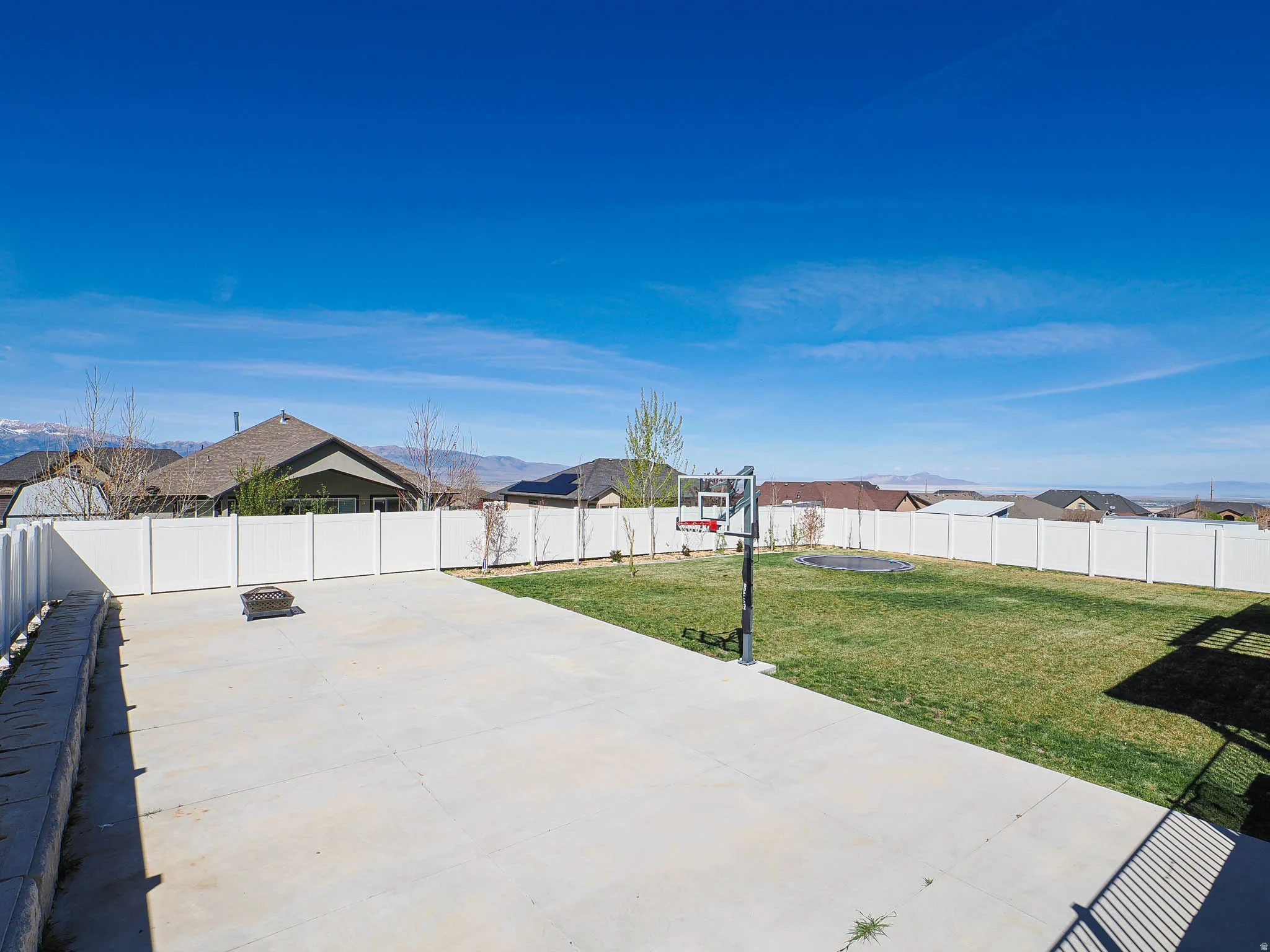Fenced backyard featuring an outdoor fire pit and a residential view