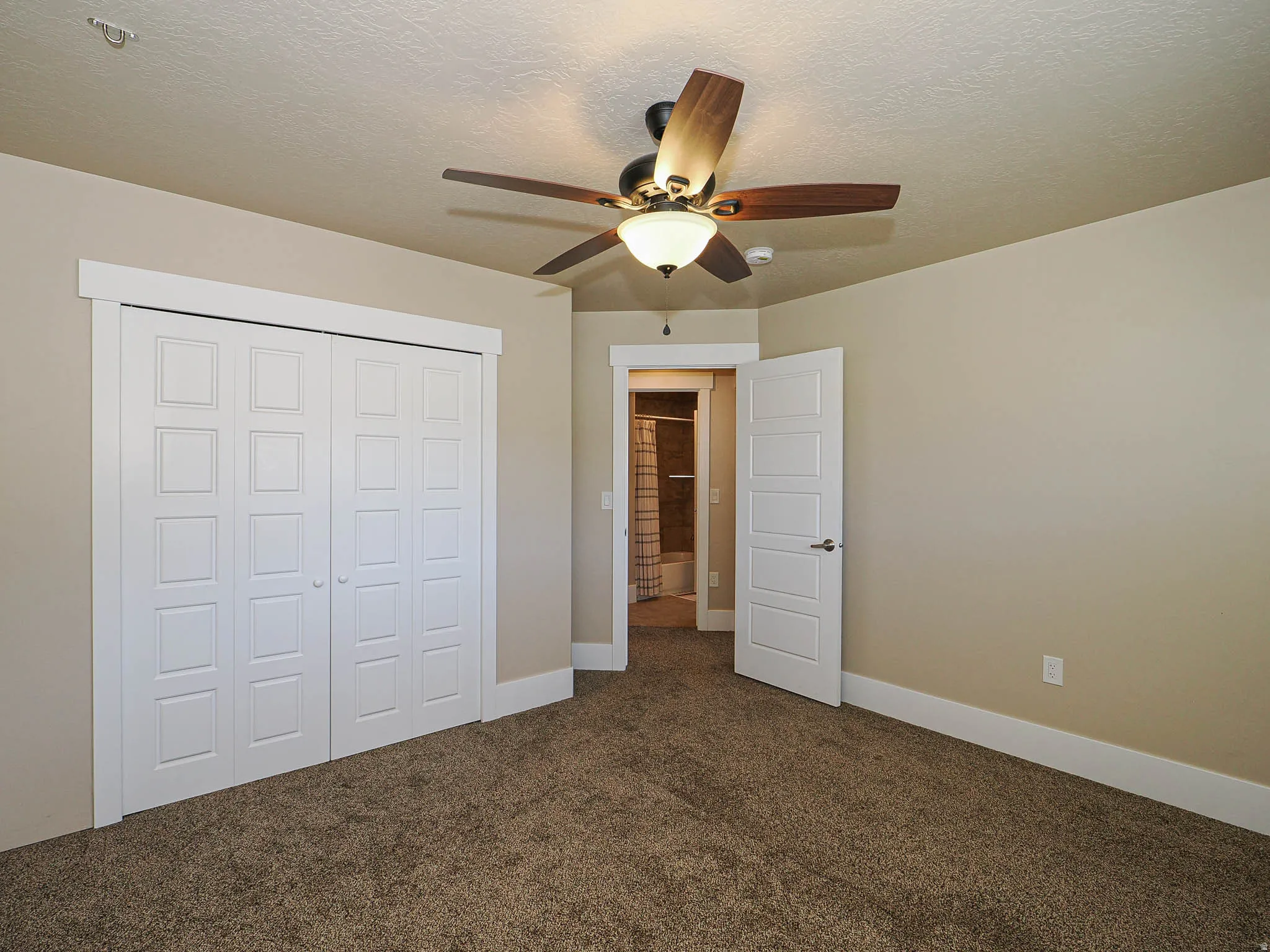 Unfurnished bedroom with dark colored carpet, a closet, a textured ceiling, and ceiling fan