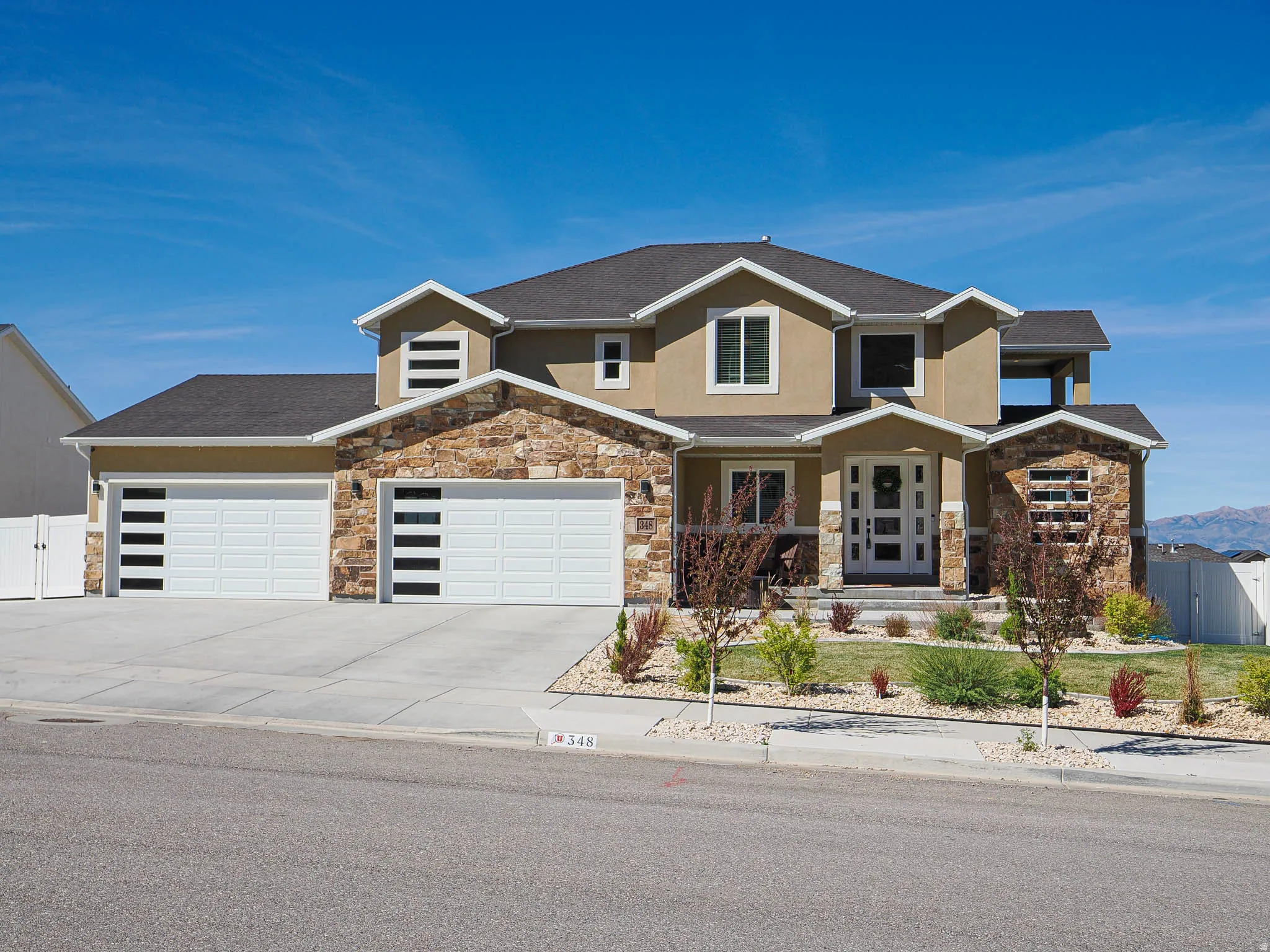 View of front facade featuring an attached garage, stone siding, stucco siding, and concrete driveway