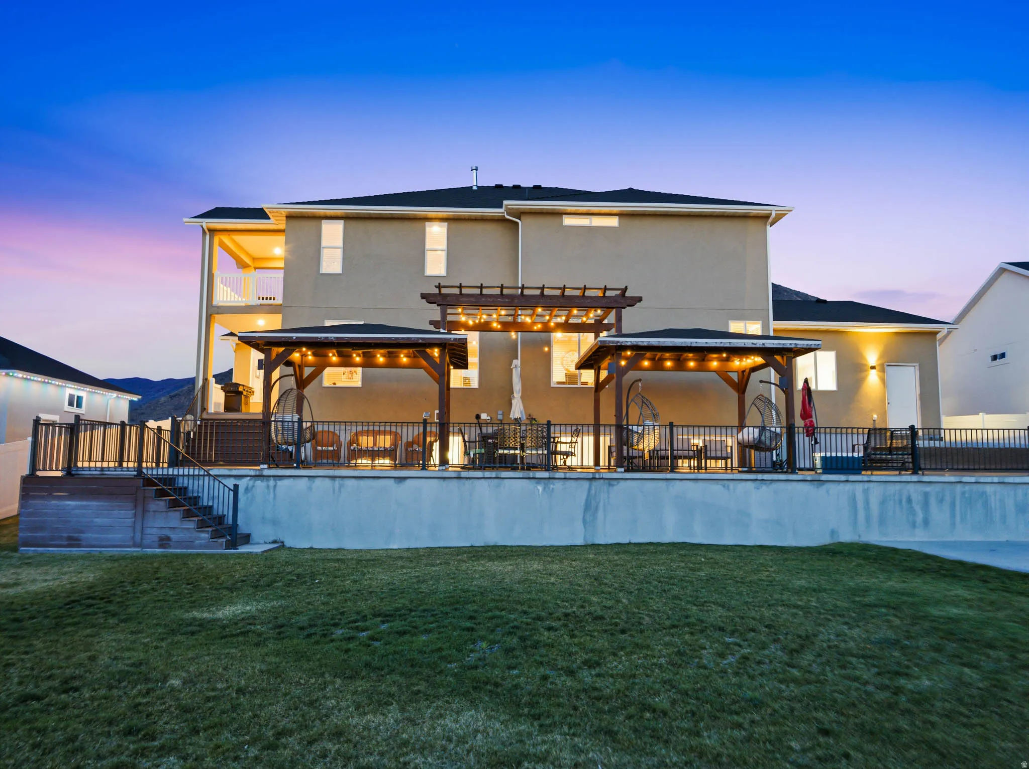 Back of property at dusk featuring a patio, stucco siding, and an outdoor pool