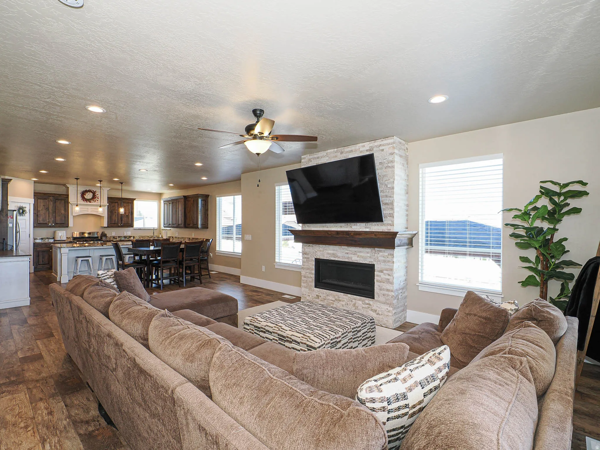 Living room featuring ceiling fan, dark wood-type flooring, a fireplace, a textured ceiling, and recessed lighting