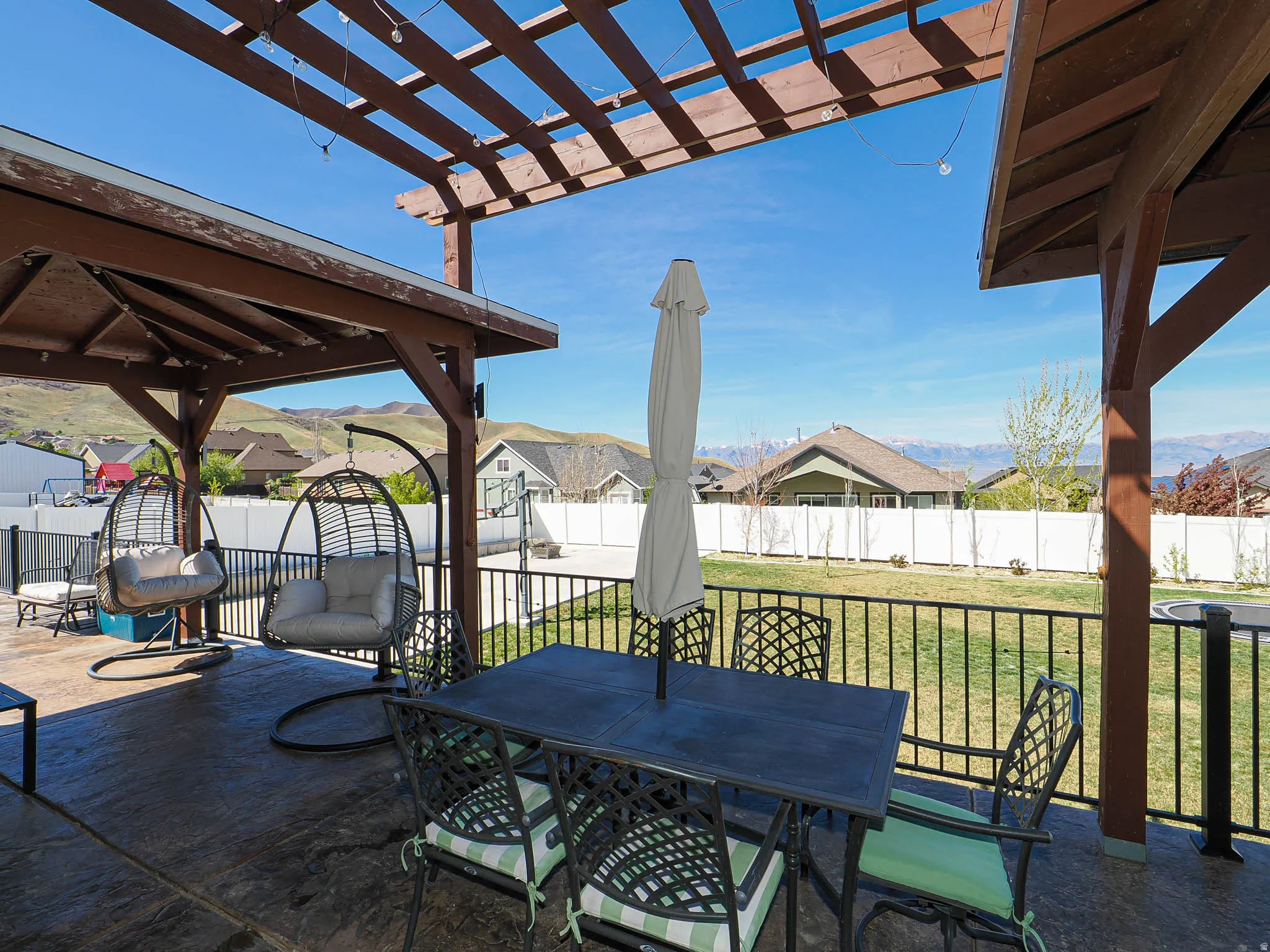Fenced backyard featuring outdoor dining space, a patio area, a gazebo, a pergola, and a mountain view