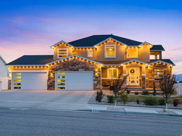 View of front of home with stone siding, a garage, and concrete driveway