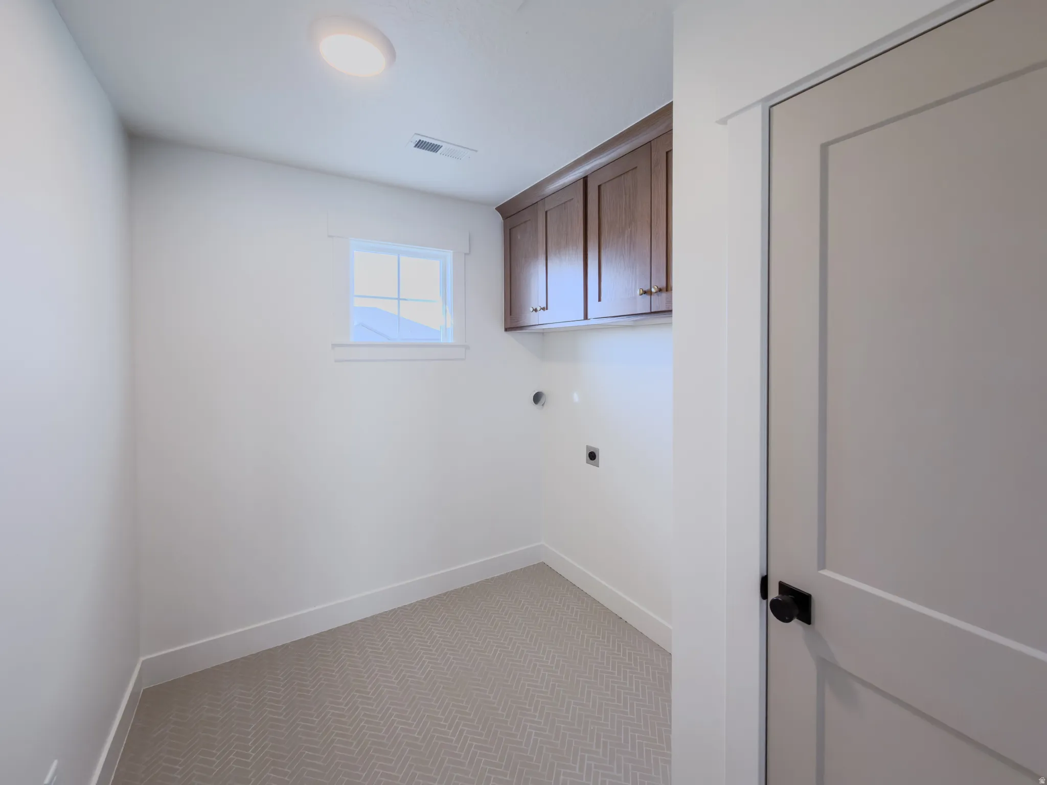 Laundry room with light carpet, hookup for an electric dryer, and cabinet space
