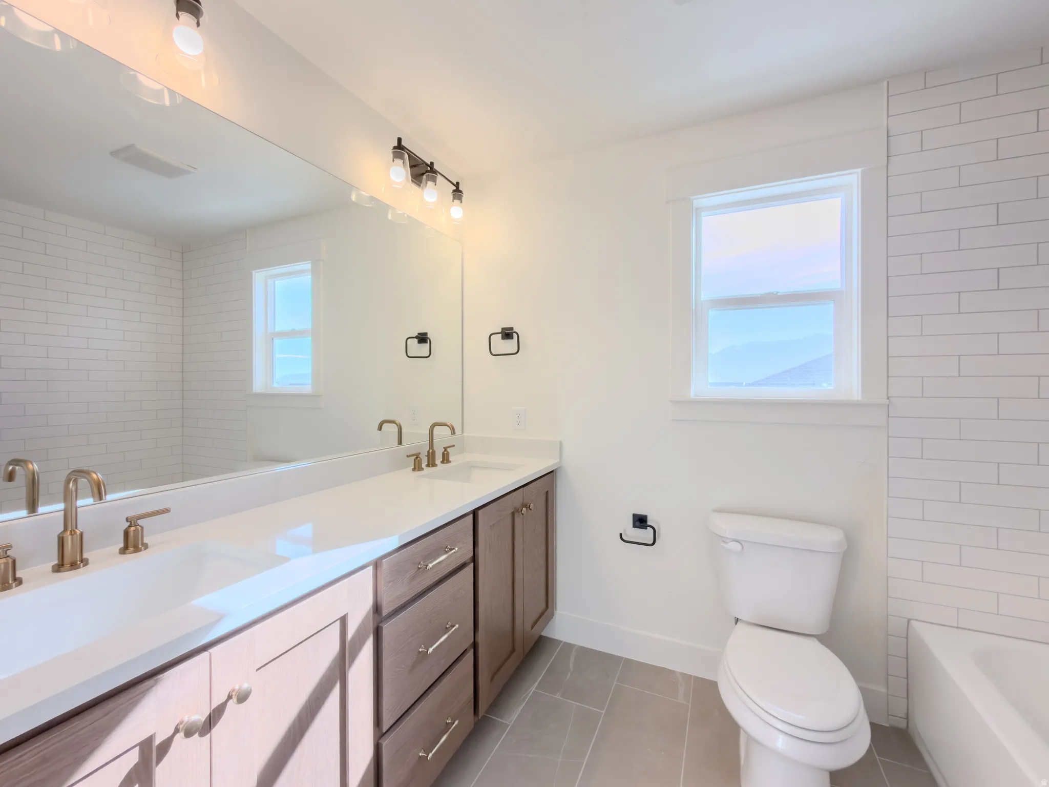 Bathroom with double vanity and light tile patterned flooring