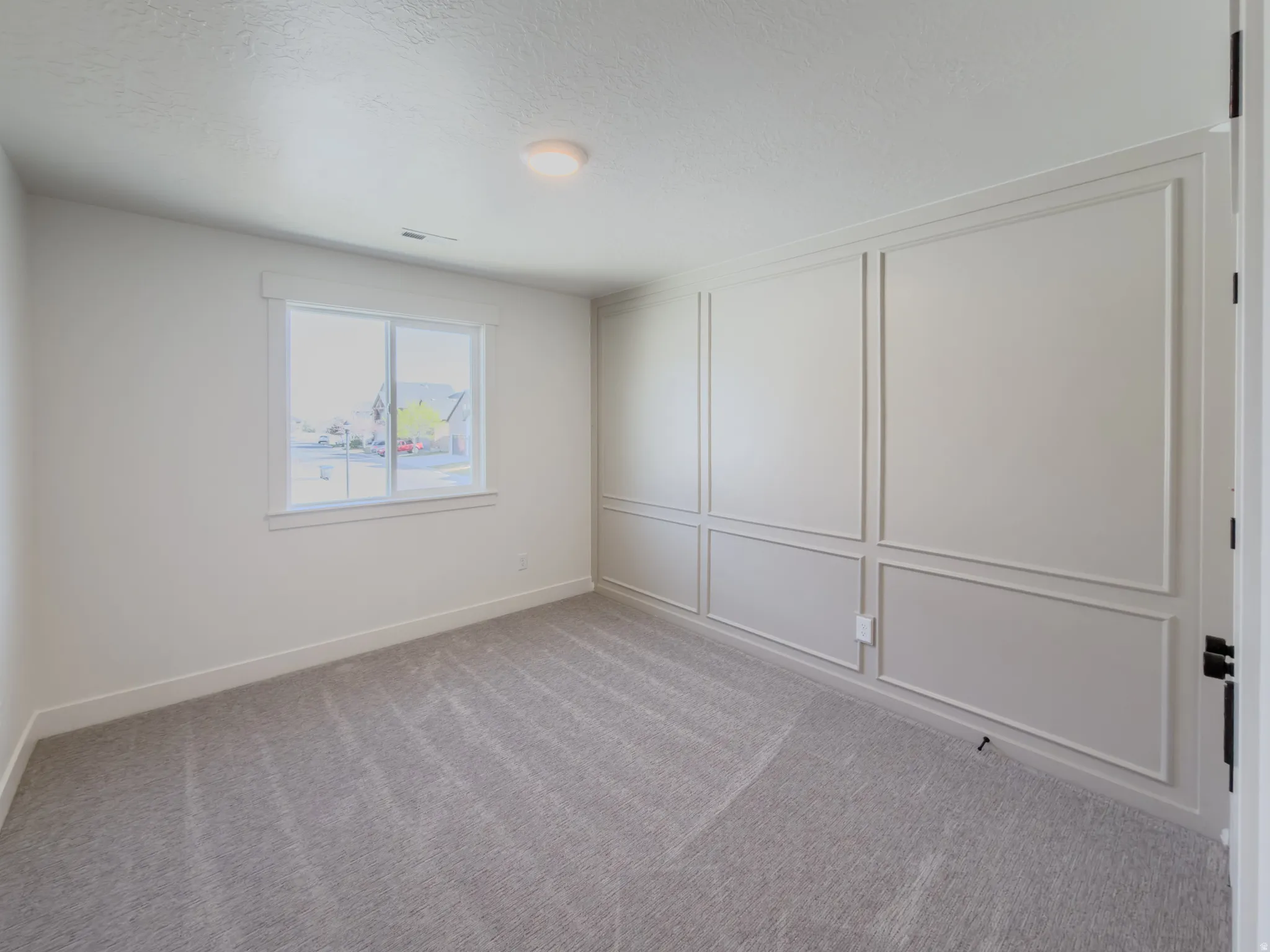 Unfurnished room with a decorative wall, light colored carpet, and a textured ceiling
