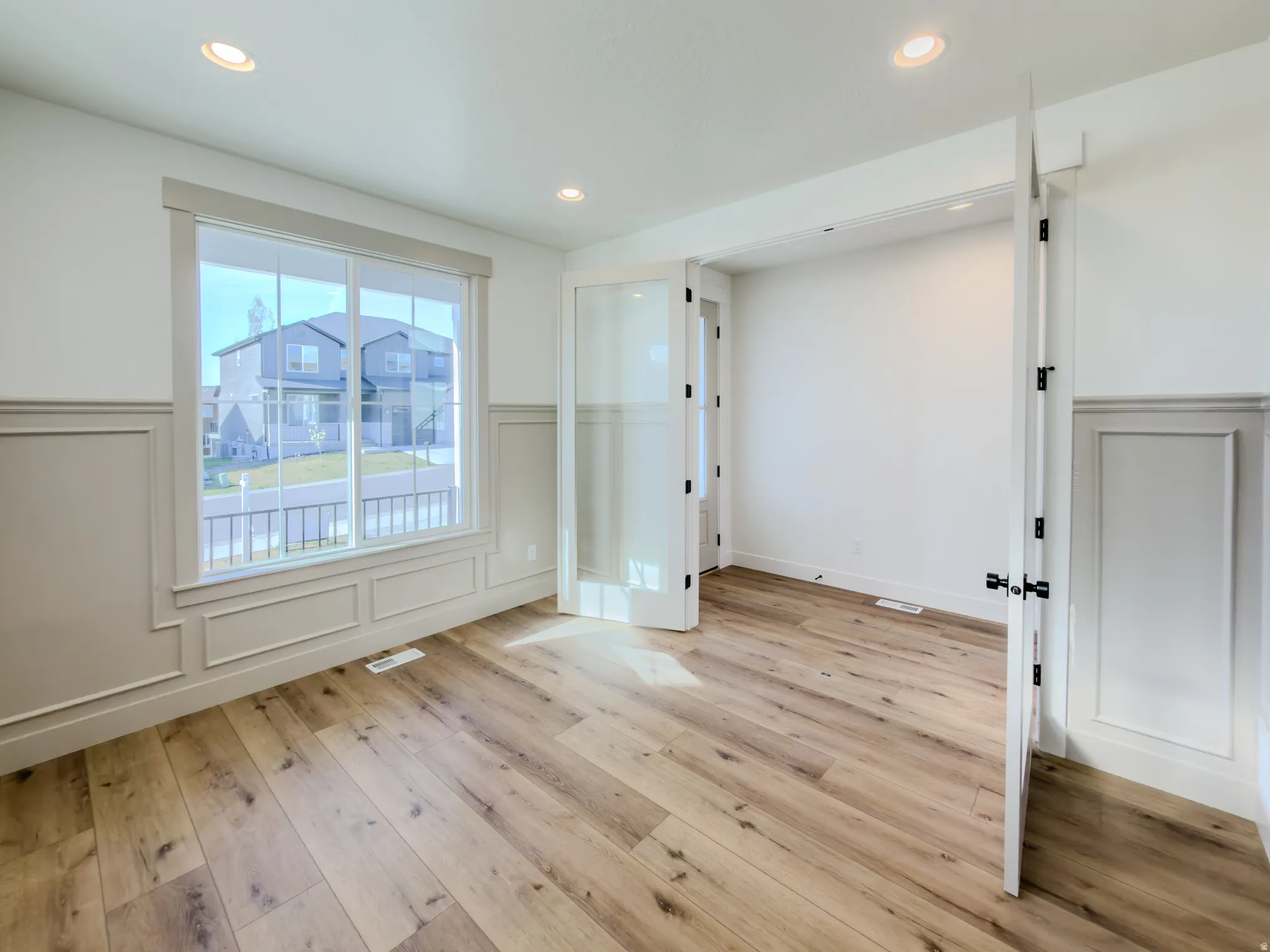 Unfurnished room featuring a wainscoted wall, a decorative wall, light wood-type flooring, and recessed lighting