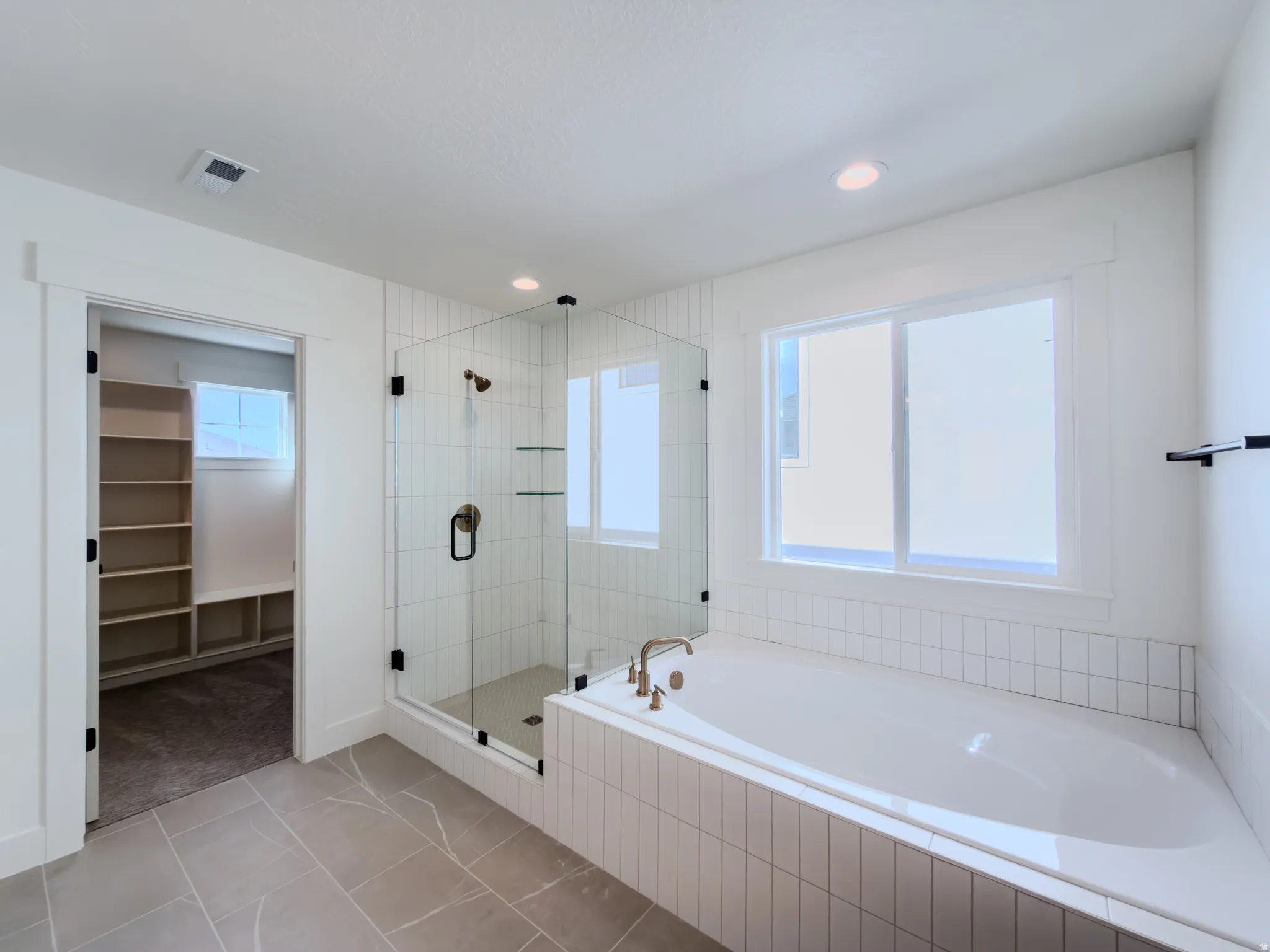 Bathroom featuring a garden tub, a stall shower, a spacious closet, light tile patterned floors, and recessed lighting