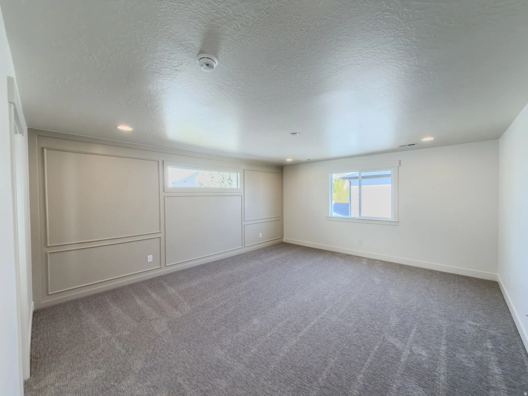 Spare room with healthy amount of natural light, light carpet, a textured ceiling, recessed lighting, and a decorative wall