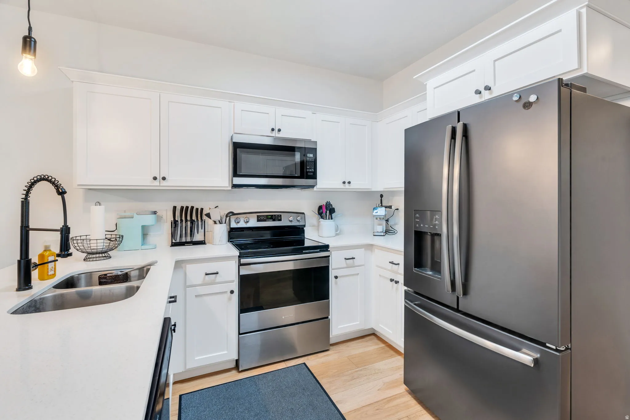 Kitchen with stainless steel appliances, white cabinetry, and light wood-type flooring. All appliances included.