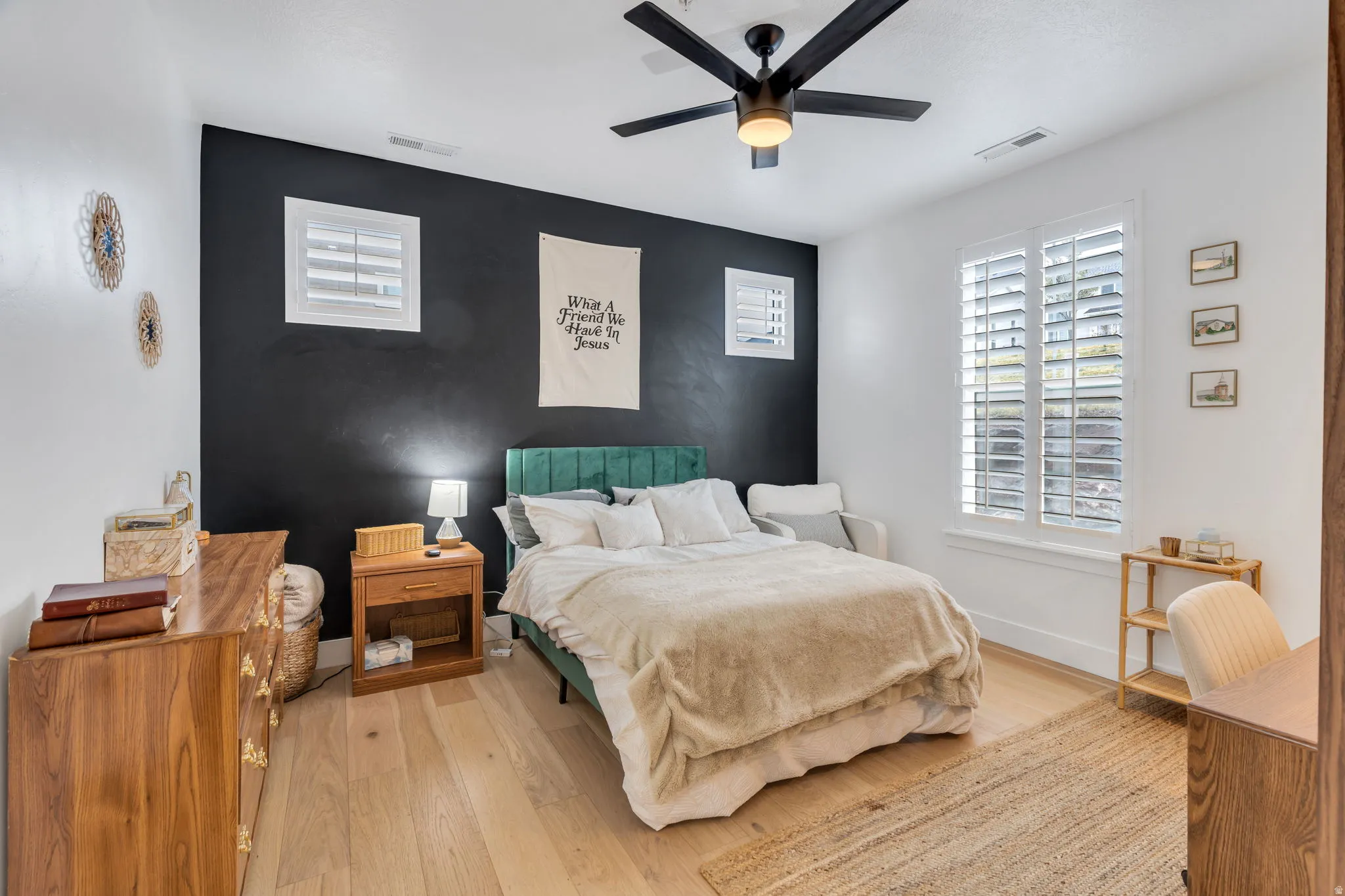 Bedroom featuring an accent wall, wood finished floors, and ceiling fan