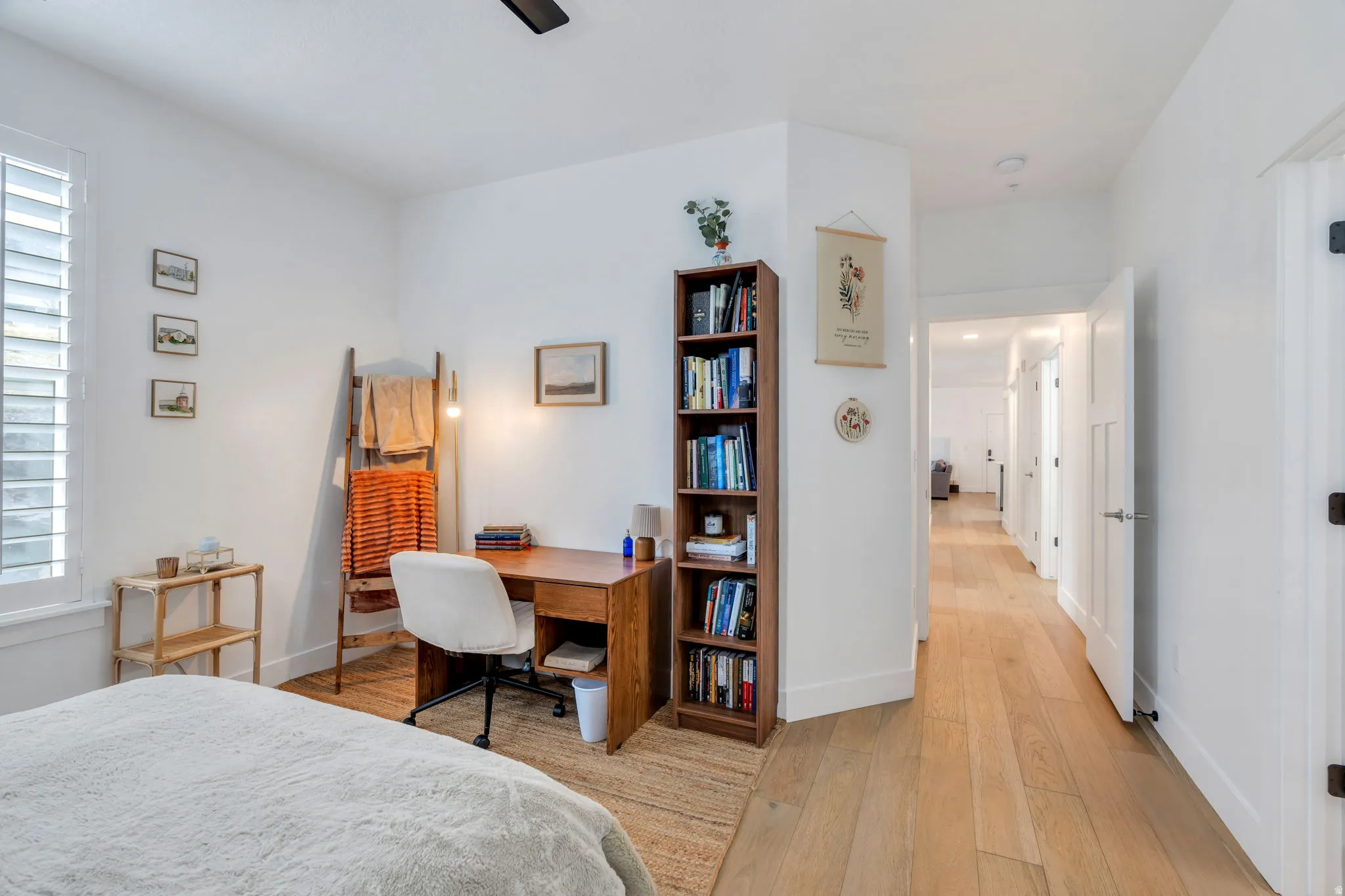 Bedroom with light wood-type flooring, ceiling fan, and an office area