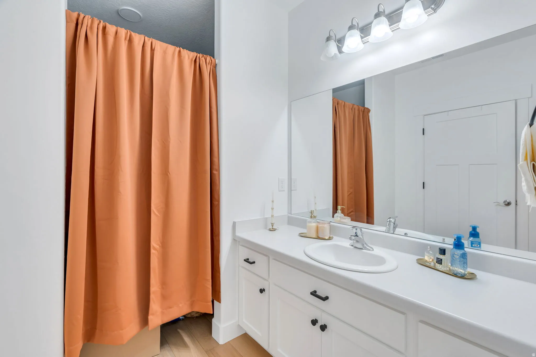 Full bath with vanity and light wood finished floors with walk in closet.