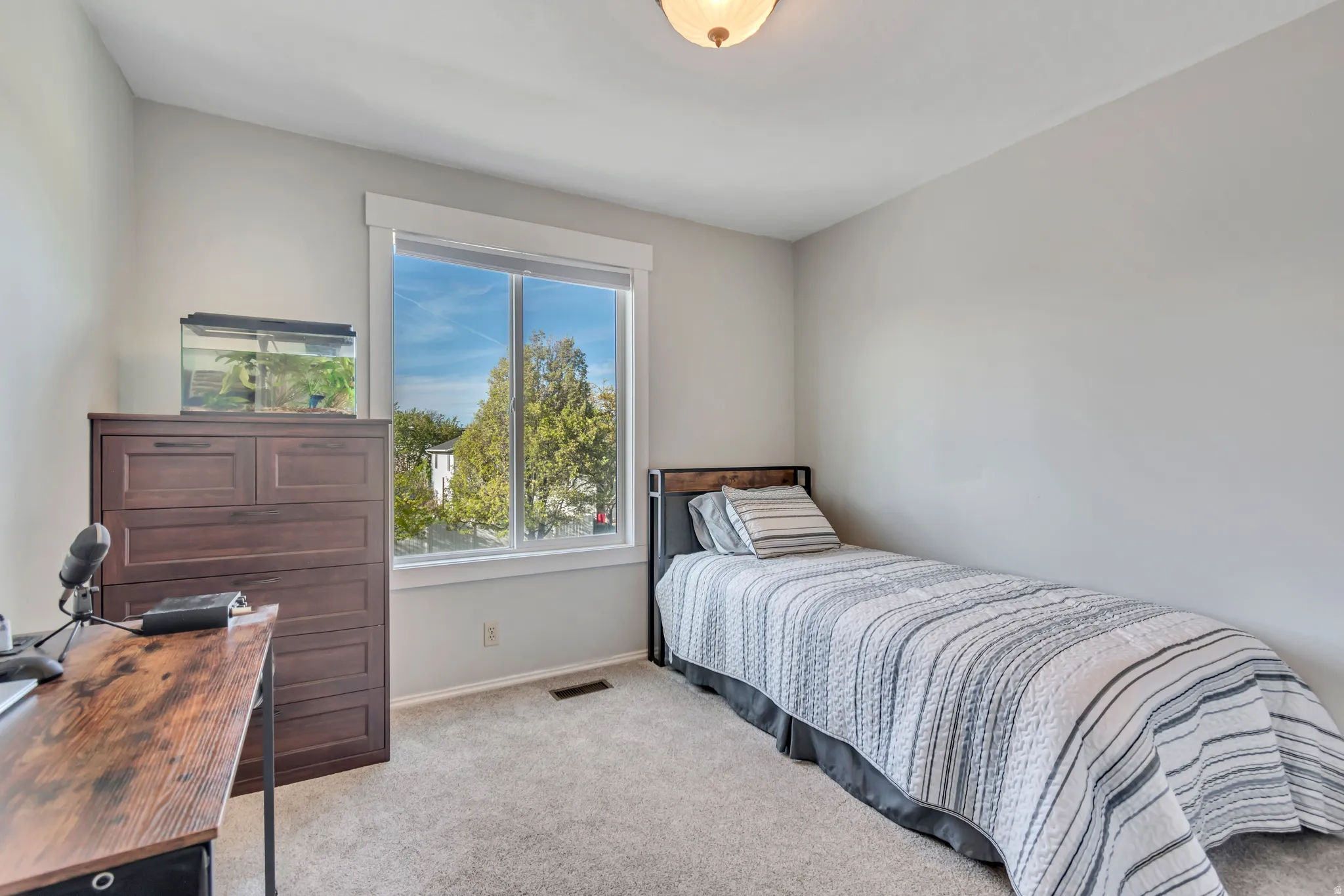 Bedroom featuring light carpet and a desk