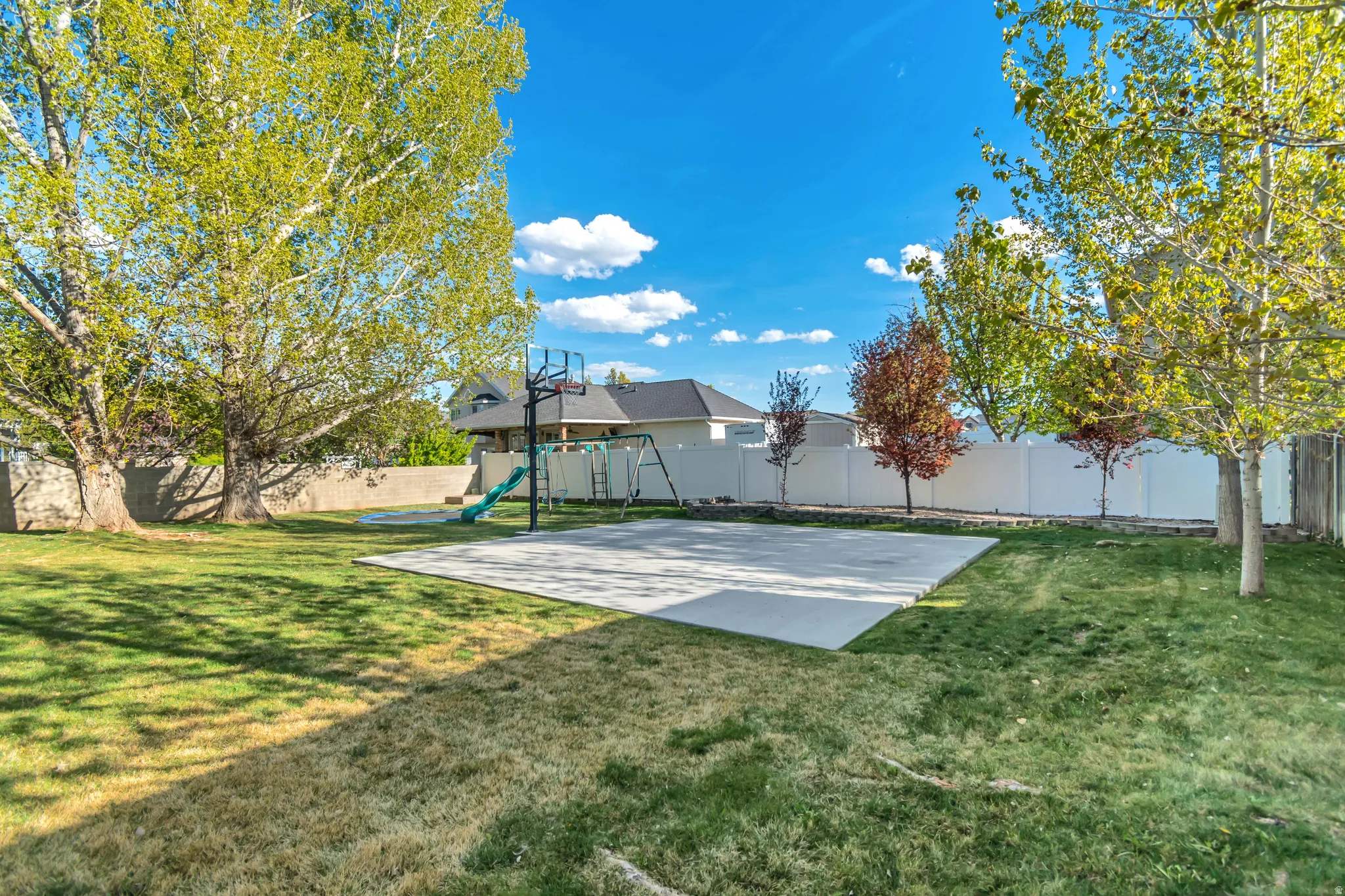 Fenced backyard featuring a patio area and basketball hoop