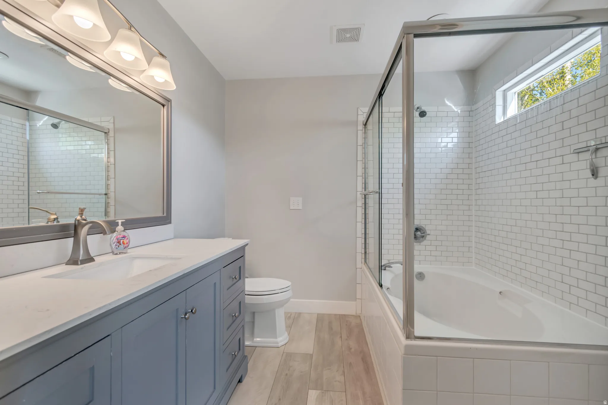 Full bath featuring vanity, light wood finished floors, and tiled shower / bath combo