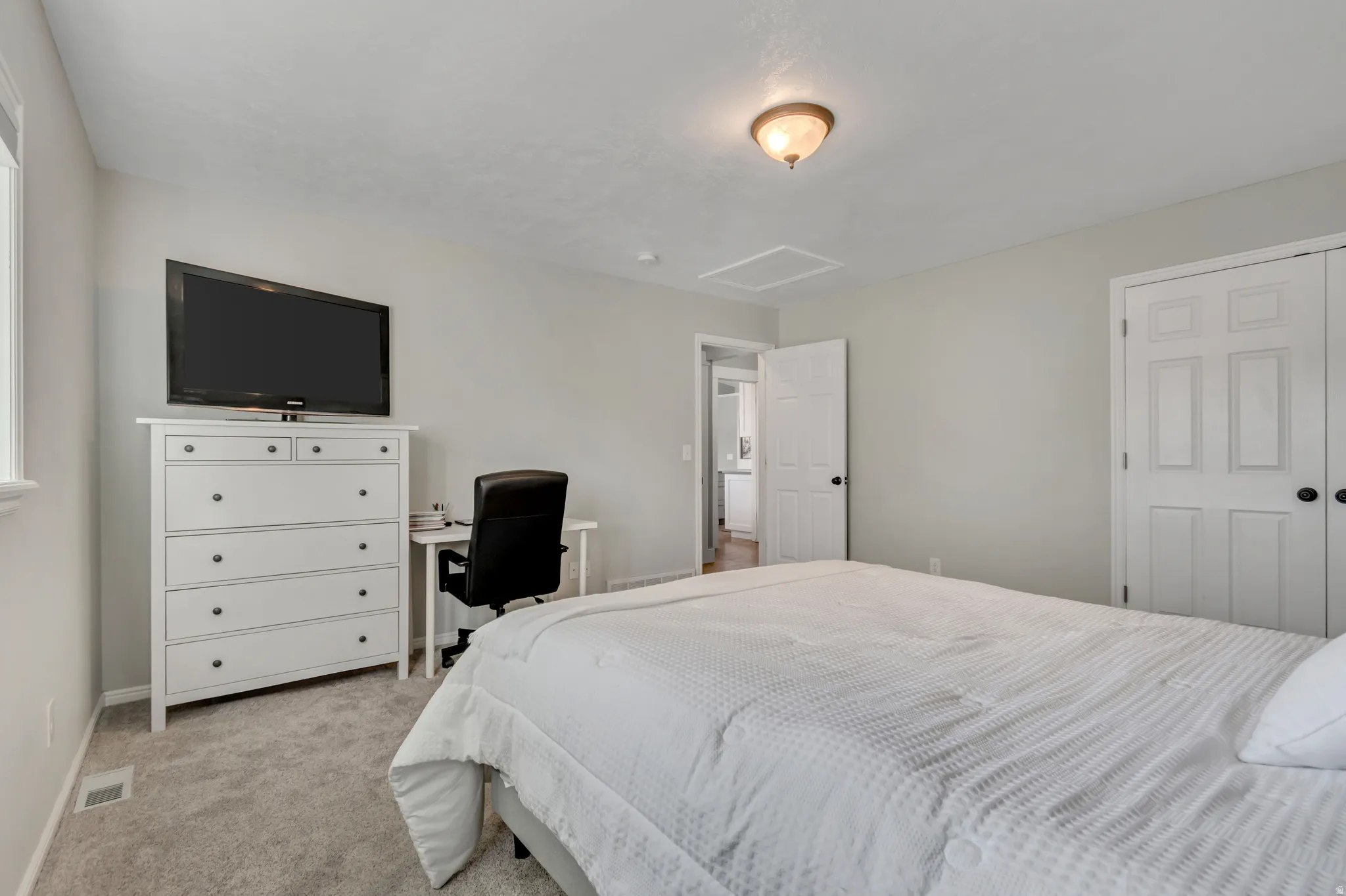Bedroom featuring light colored carpet and a desk