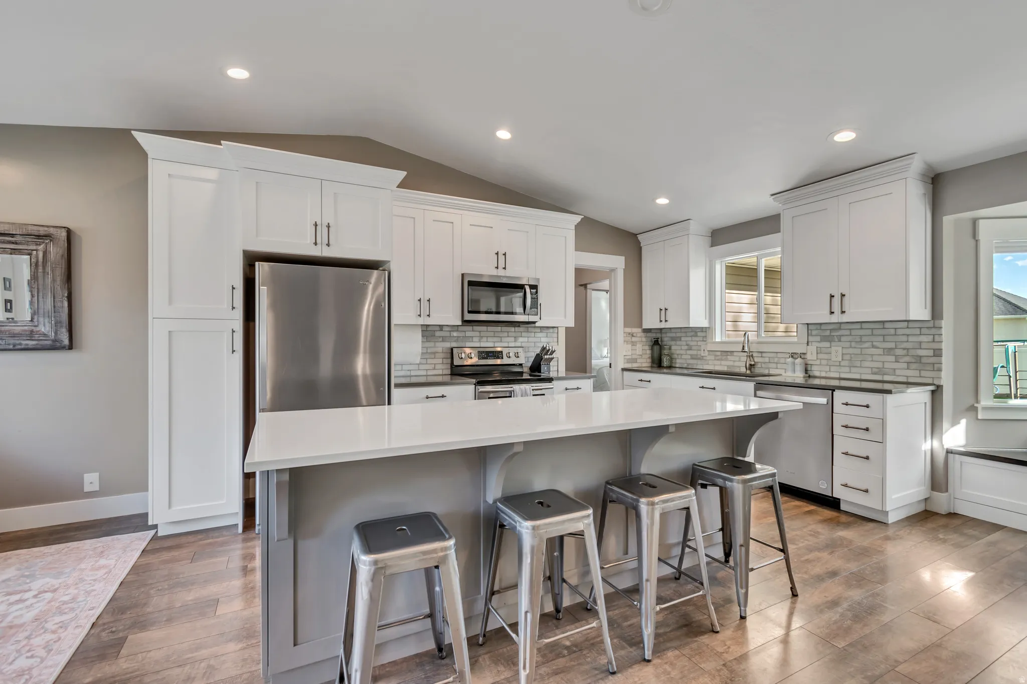 Two tone kitchen with stainless steel appliances, a breakfast bar, a kitchen island, tasteful backsplash, and light wood-style flooring
