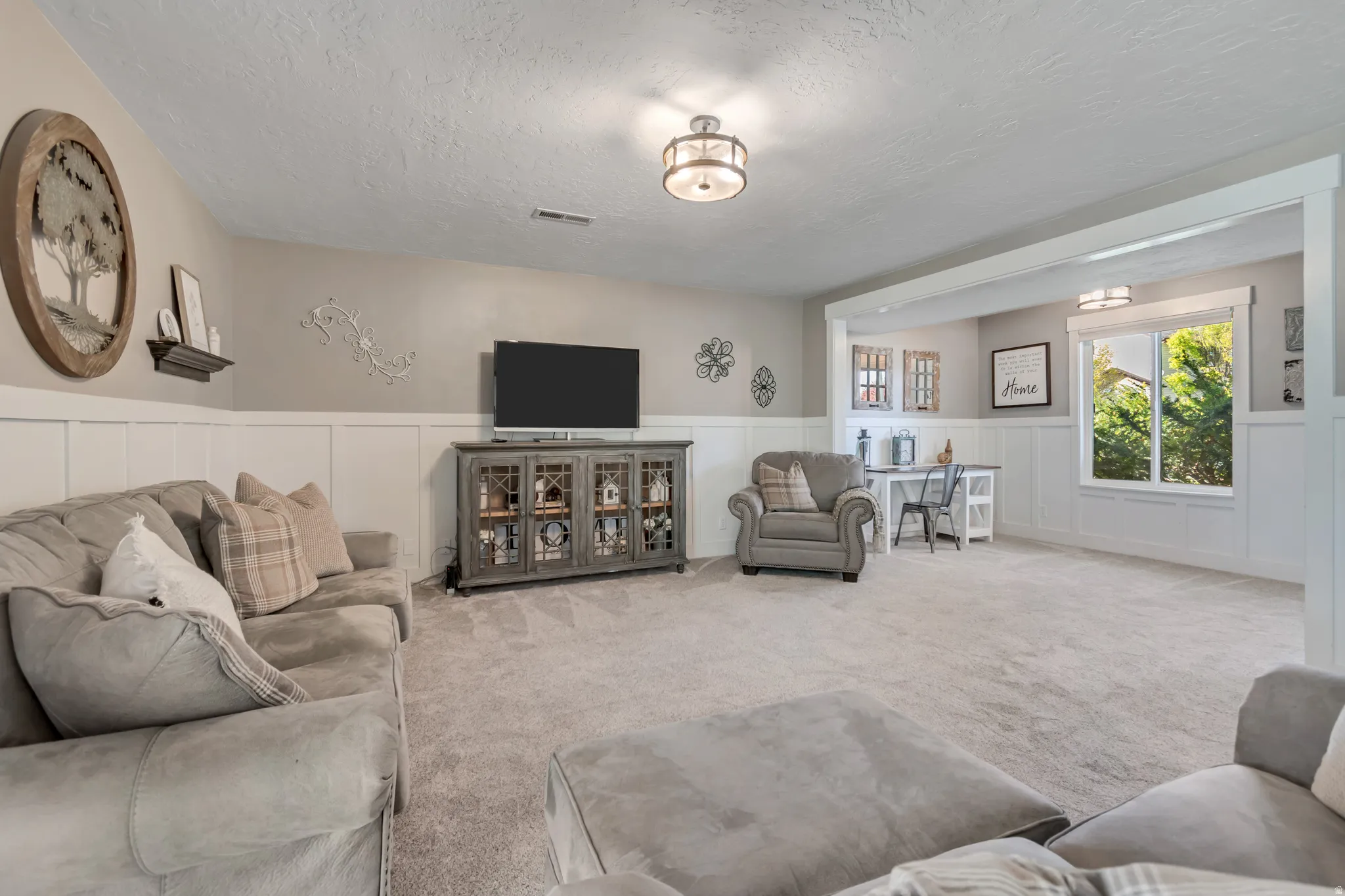 Carpeted living room with wainscoting, a decorative wall, and a textured ceiling