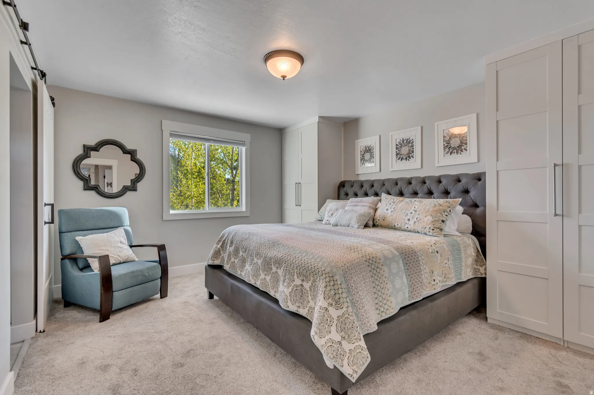 Bedroom featuring a barn door and light carpet